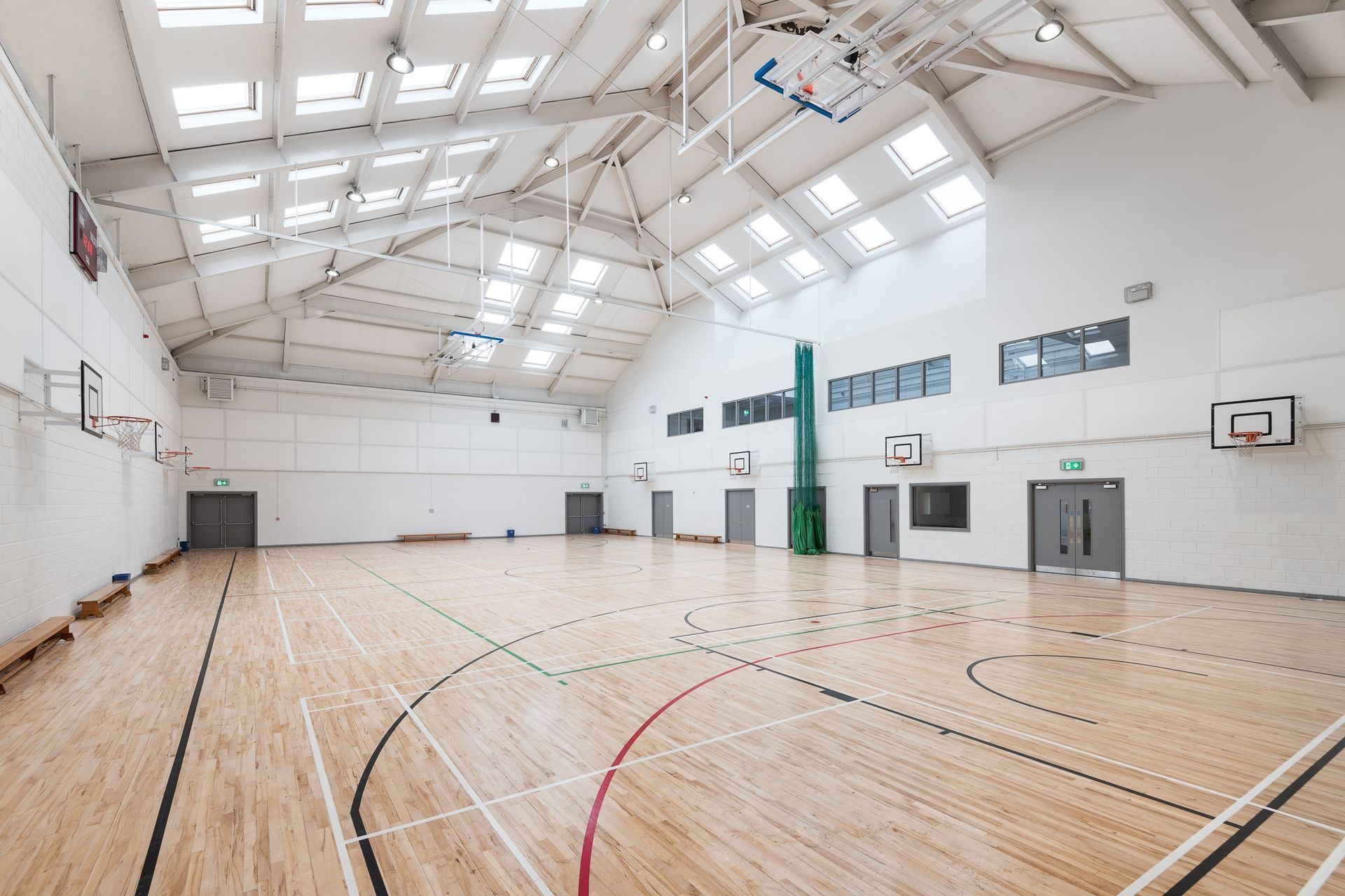 A large indoor basketball court with a wooden floor and a basketball hoop.