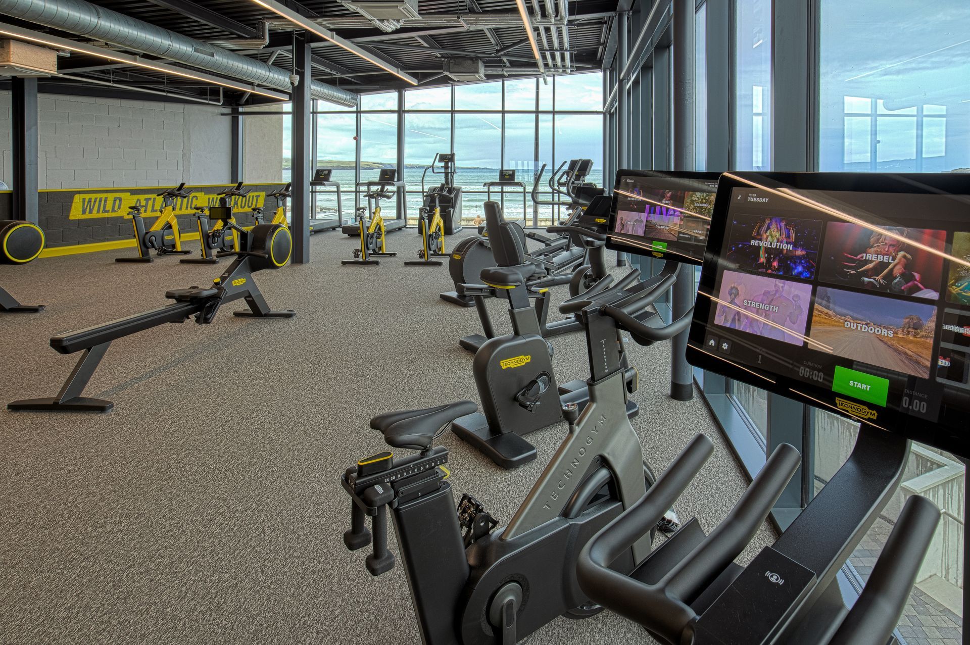 A gym with a lot of exercise equipment and a large window.
