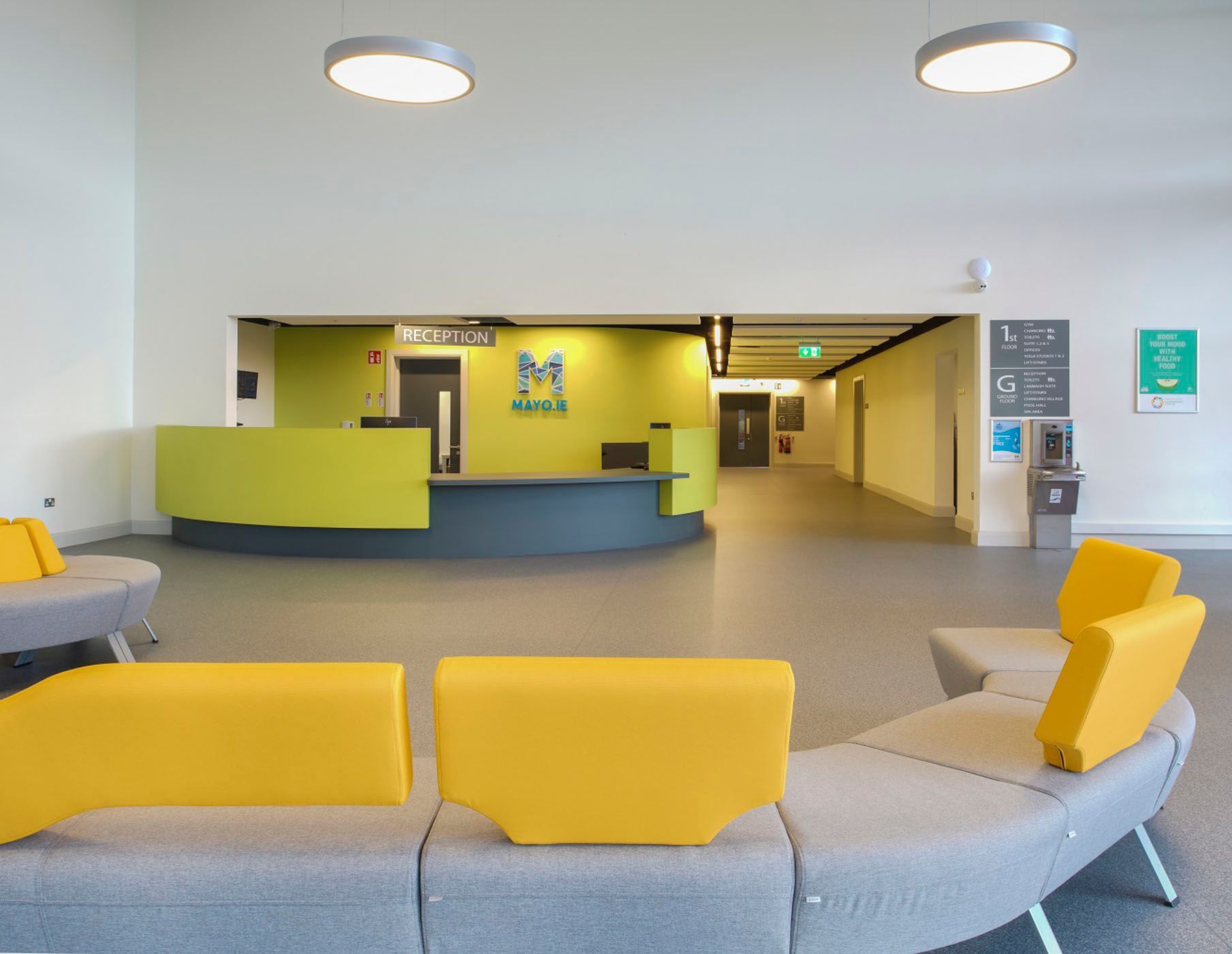 A lobby with yellow couches and a green counter.