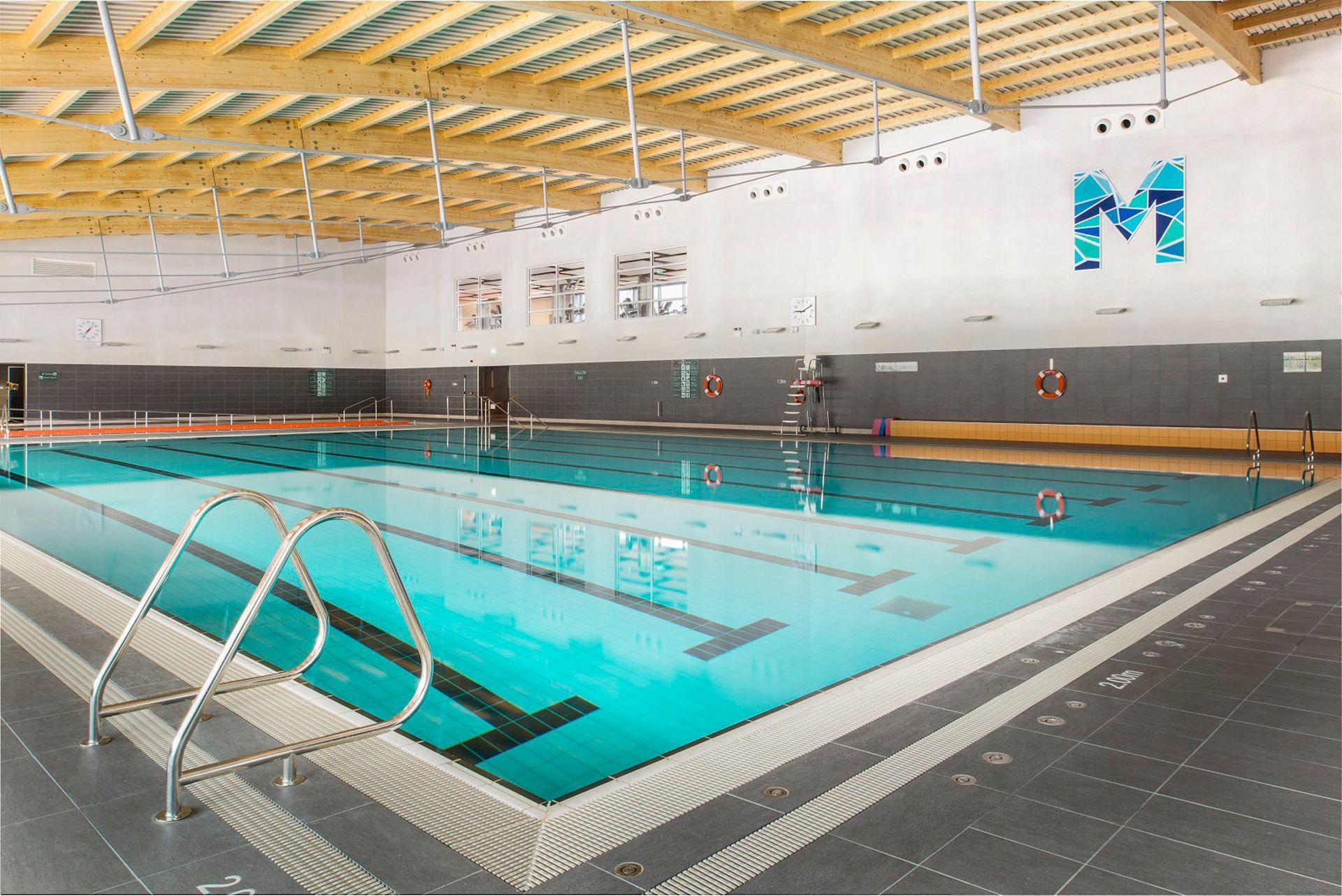 A large indoor swimming pool with the letter m on the wall