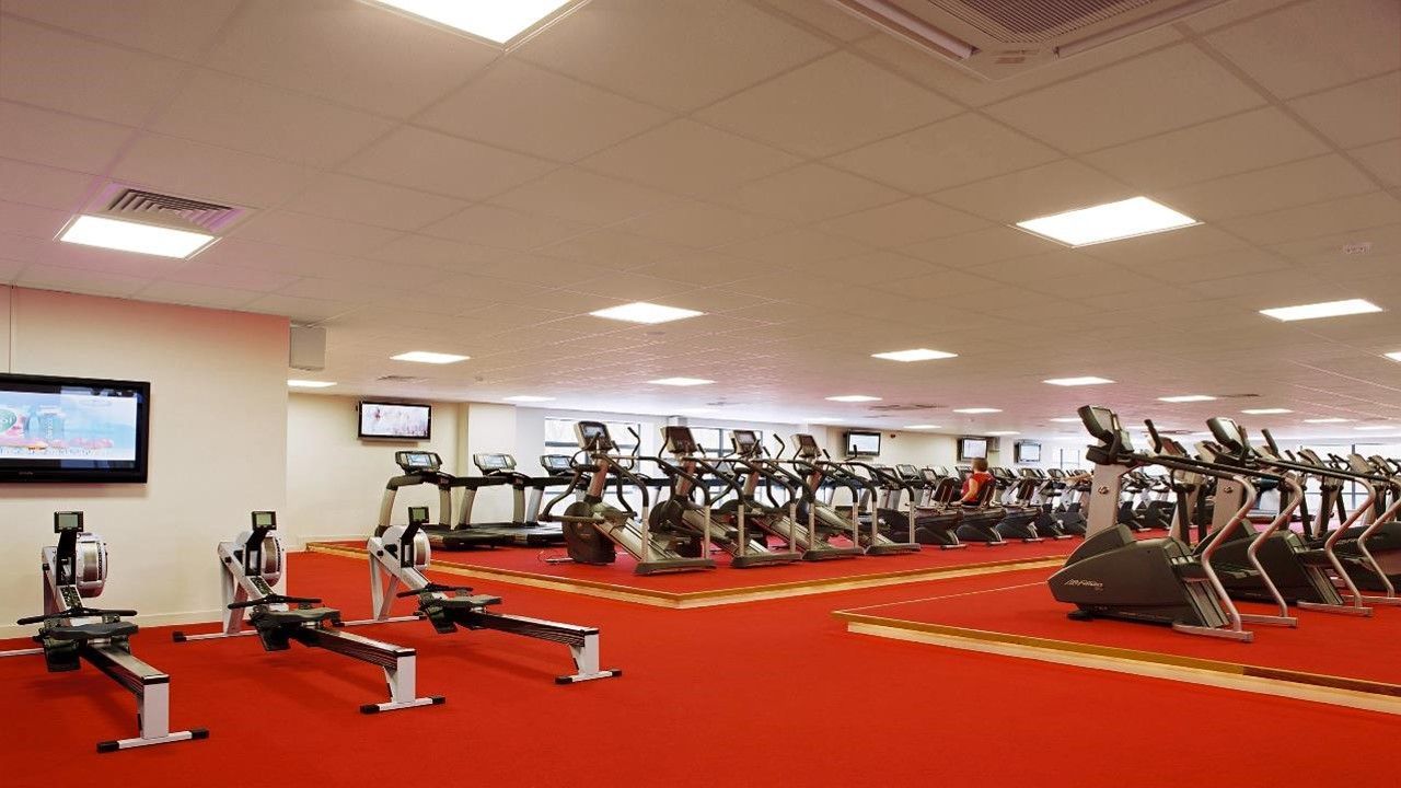 A large gym with a lot of exercise equipment and a red carpet.