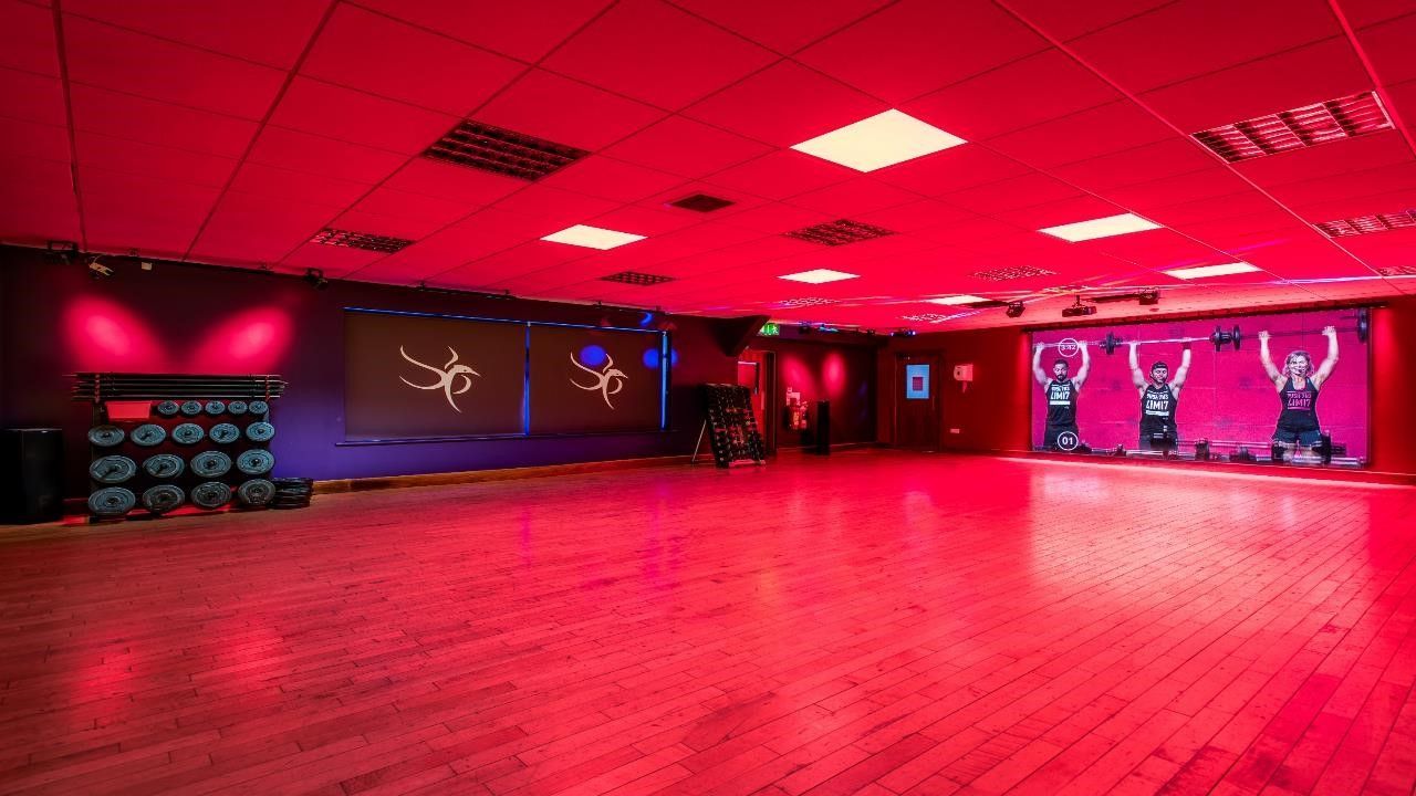 A large empty dance studio with red lights on the ceiling.