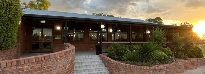 A Large Brick Building with a Covered Porch and a Sunset in The Background - Function Venue in Hillvue, NSW