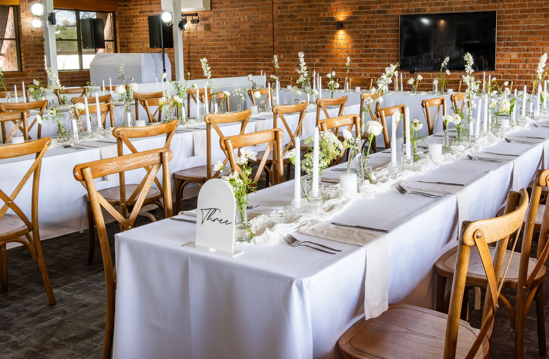 A Long Table with White Linens and Wooden Chairs is Set up for a Wedding Reception - Function Venue in Hillvue, NSW
