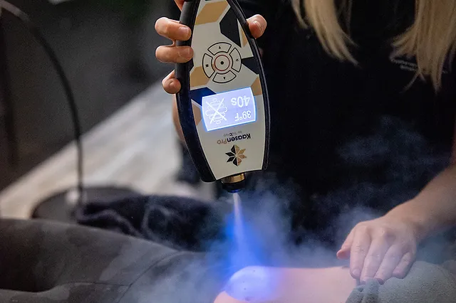 A woman is holding a device with a blue light coming out of it.