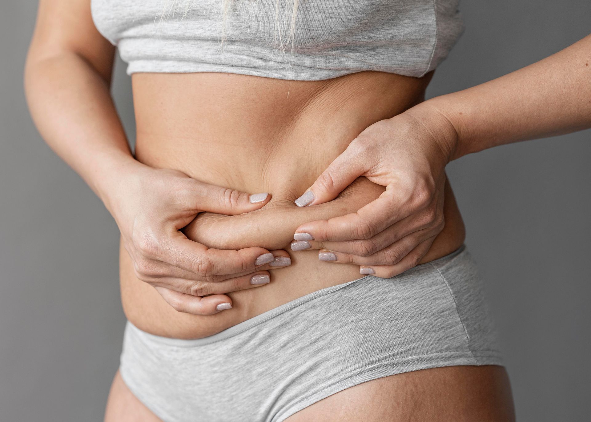 A woman is holding her stomach with her hands.