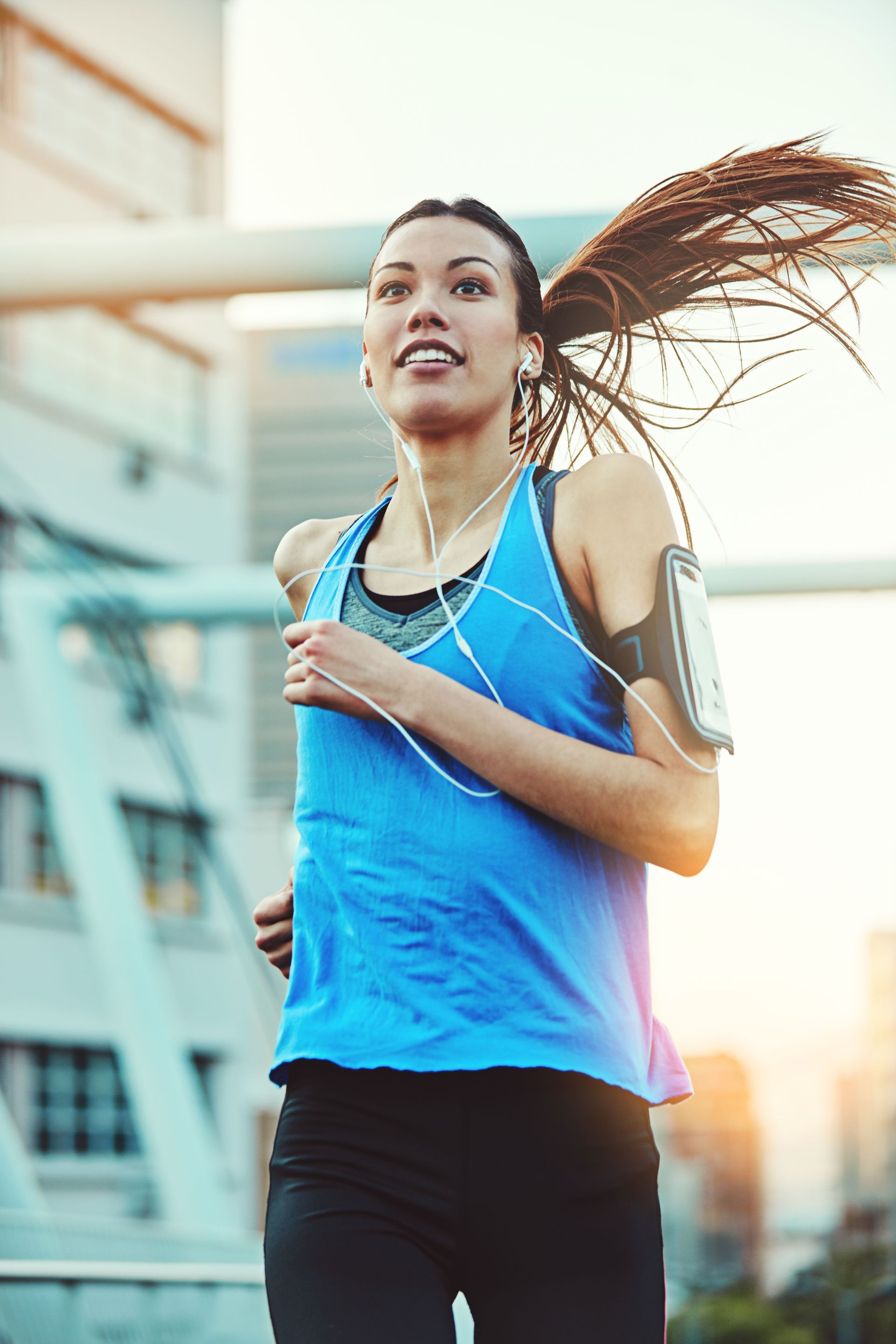 A woman is running in the city while listening to music.