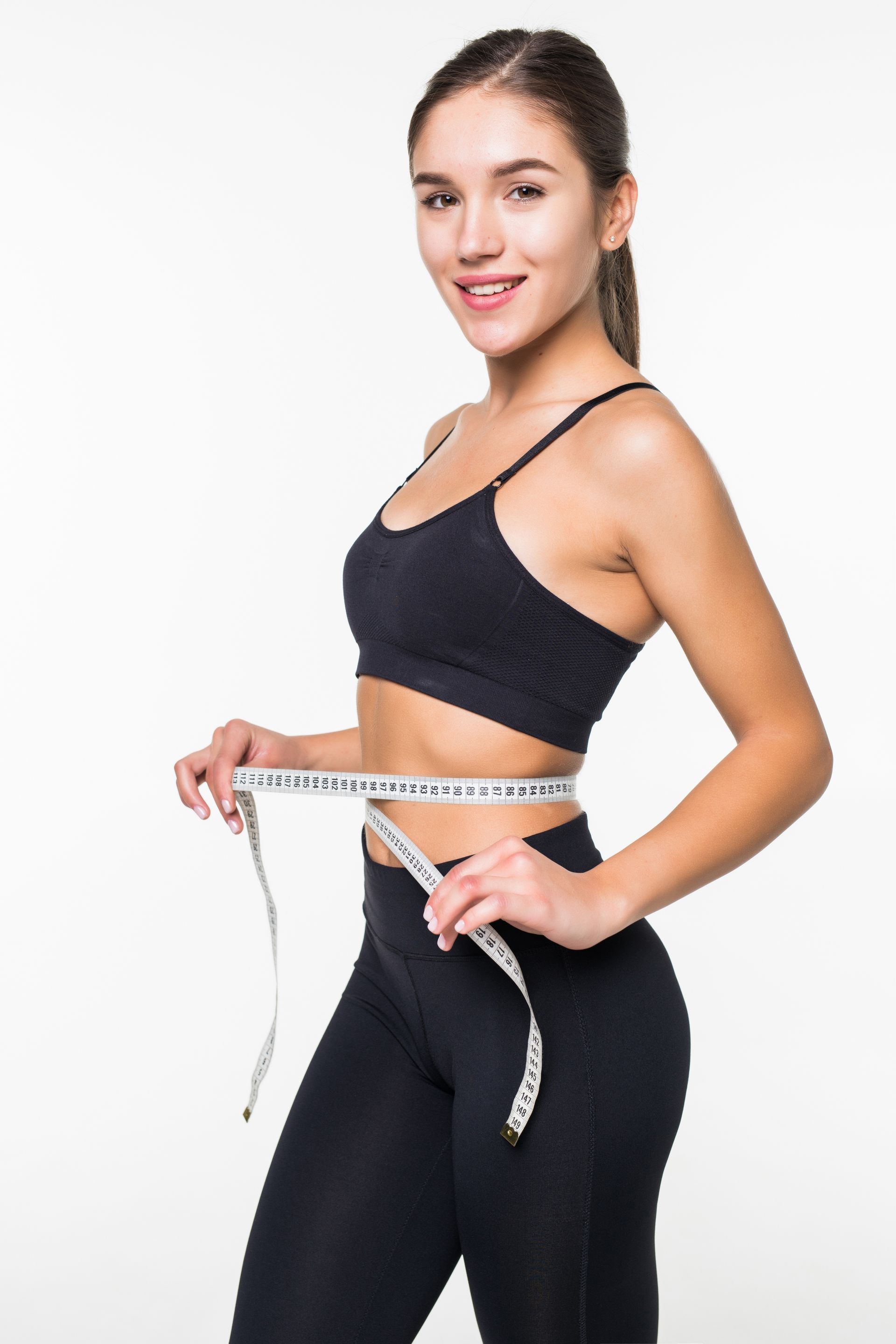 A woman is measuring her waist with a tape measure.