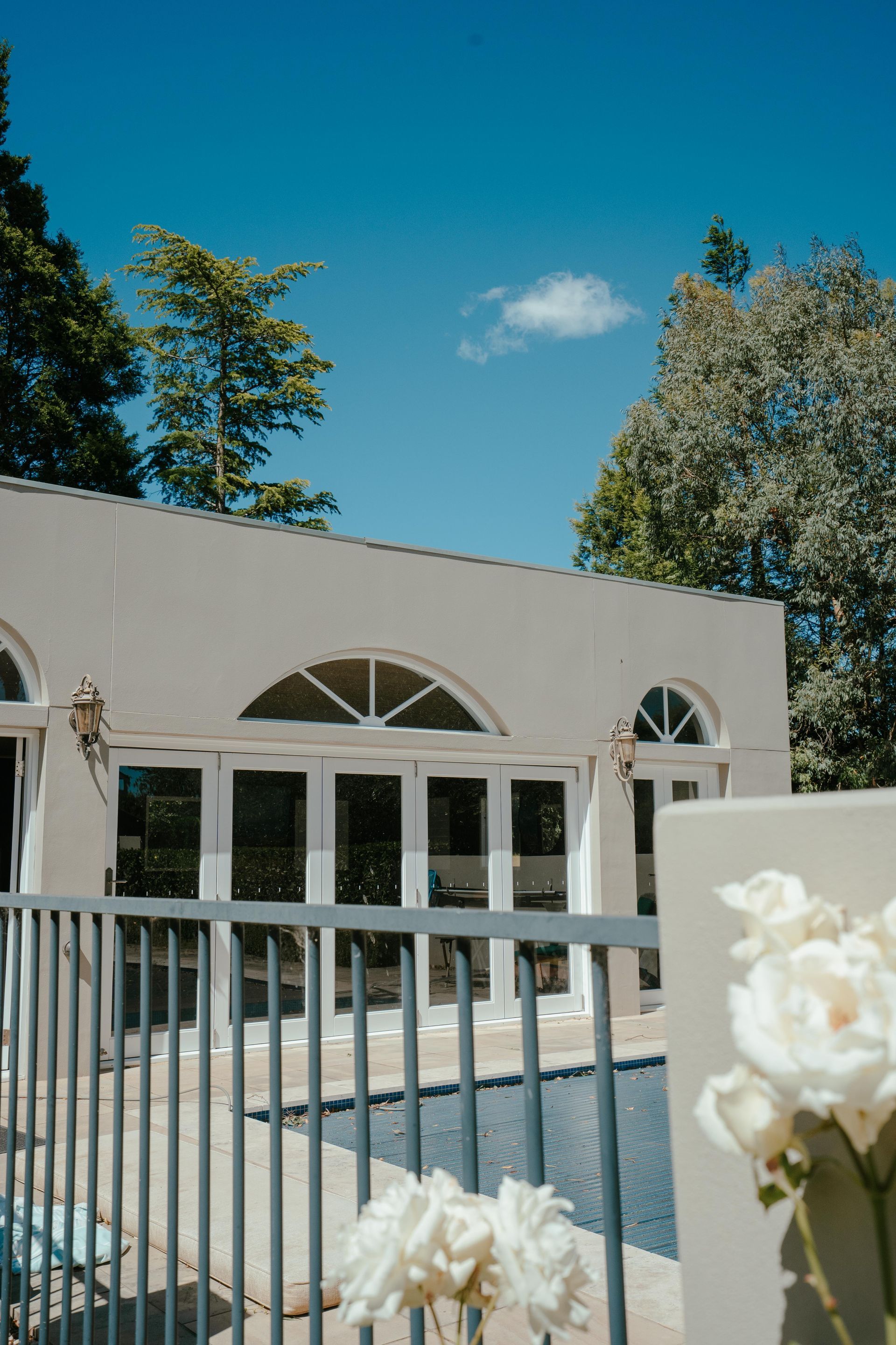 Beige Building With Arched Windows, Pool, White Roses, and Blue Sky — Mittagong Painting in Welby, NSW
