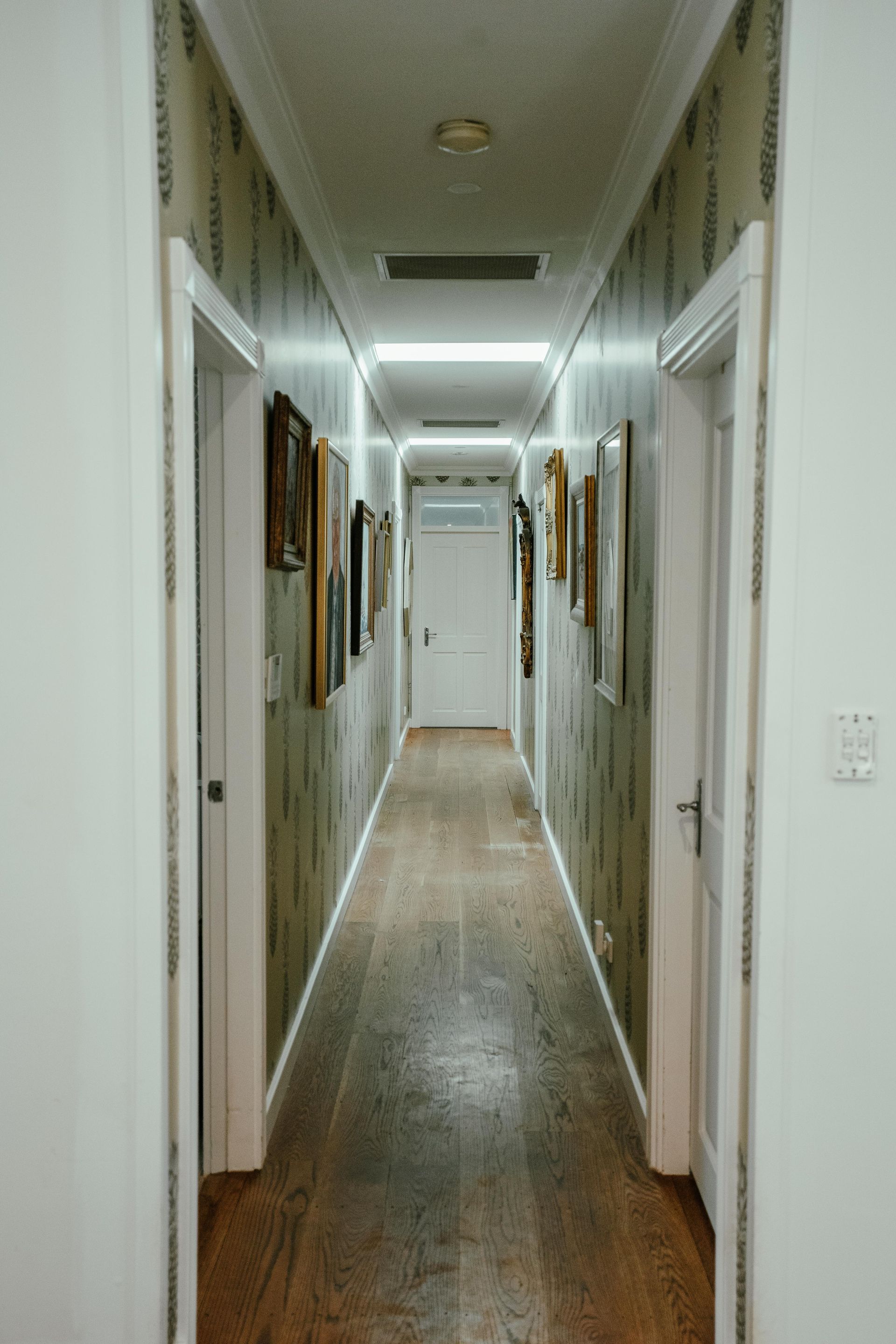 Long Hallway With Wood Flooring, Doors, and Artwork on Patterned Wallpapered Walls — Mittagong Painting in Welby, NSW
