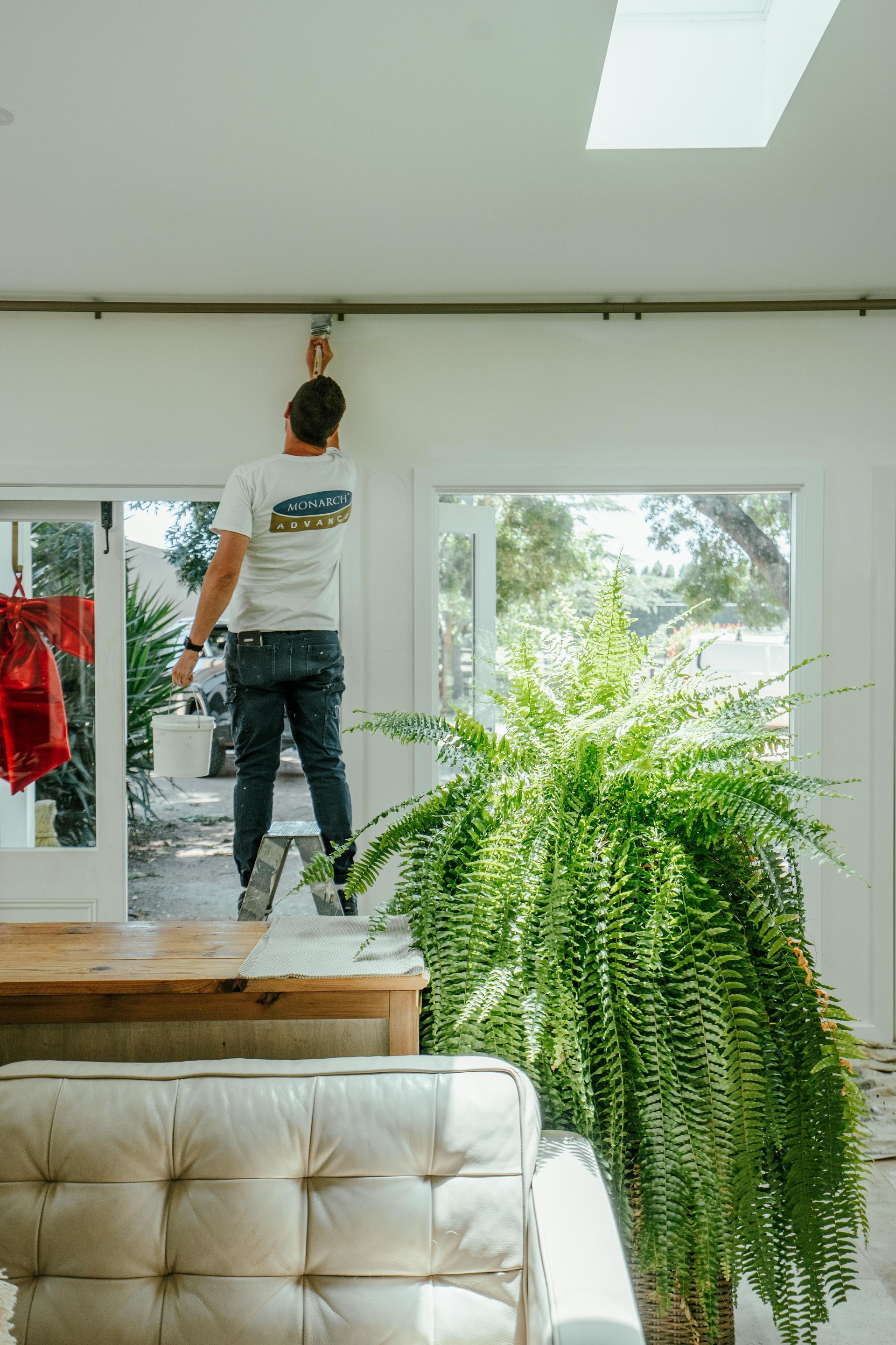 Man on a Table Paints a Ceiling Fixture — Mittagong Painting in Welby, NSW