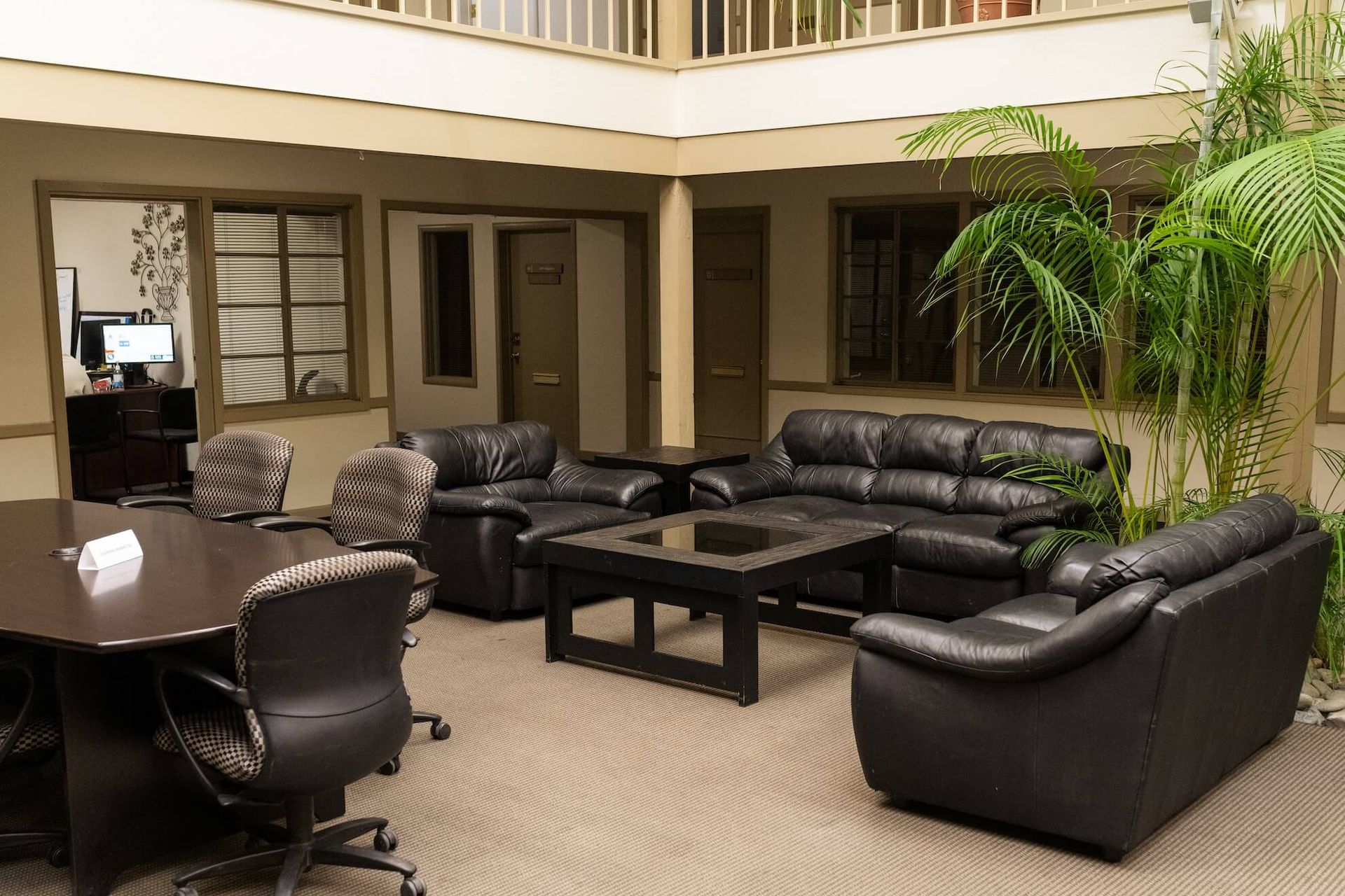 U-shaped office desk with built-in overhead cabinets and a window with blinds.