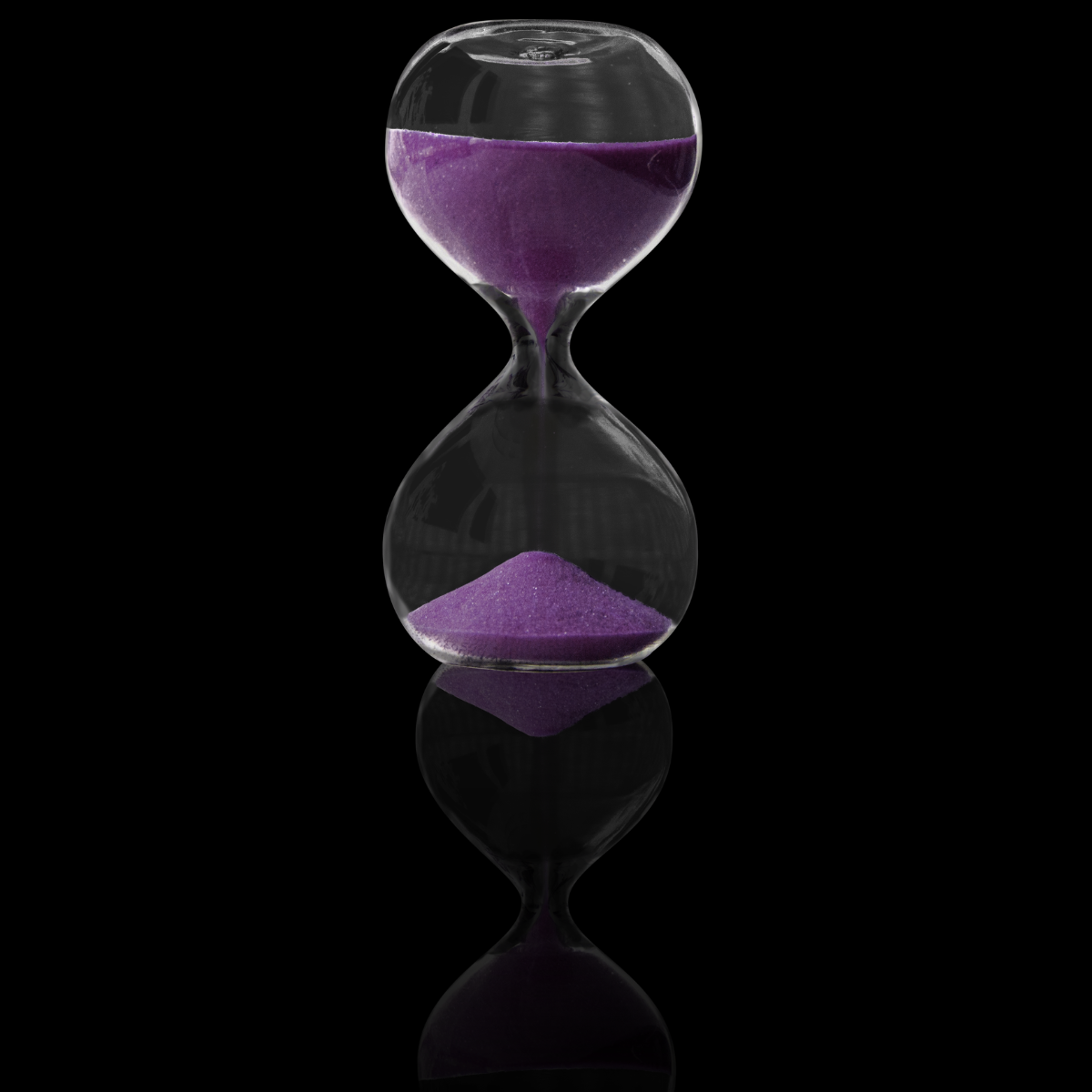 Purple sand in a clear hourglass on a black background
