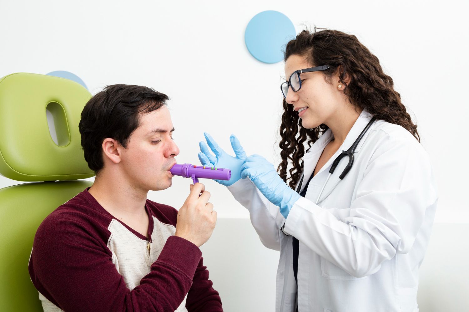Doctor examining man with spirometer in a clinic, with blue gloves and green wall decor