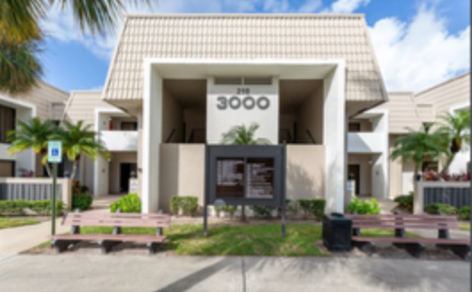 Modern beige apartment entrance with the number 3000, palm trees, and a covered walkway