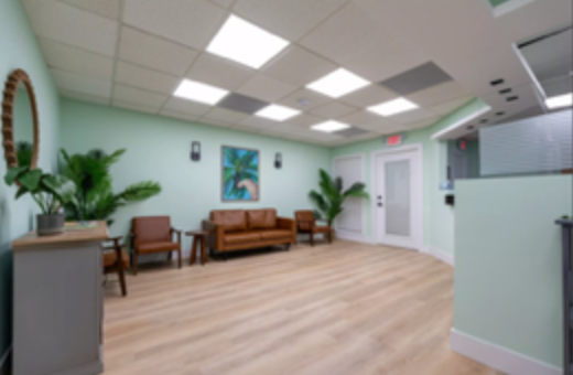 Bright waiting room with wooden benches, plants, pale green walls, and skylights
