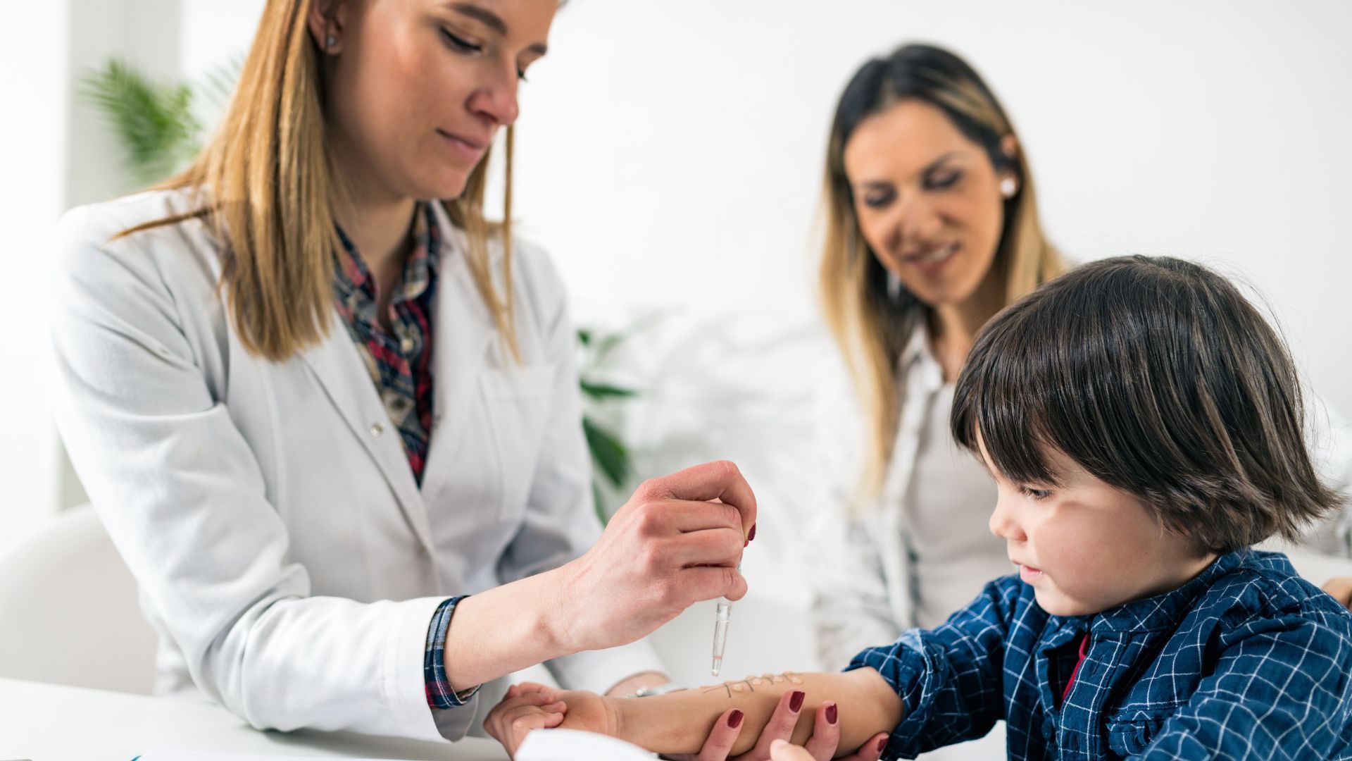 Clinician applying a bandage to a child’s hand while another adult observes in a bright medical setting