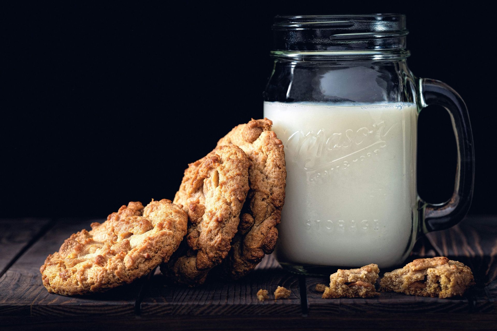 Cookies and a mason jar of milk on a dark table