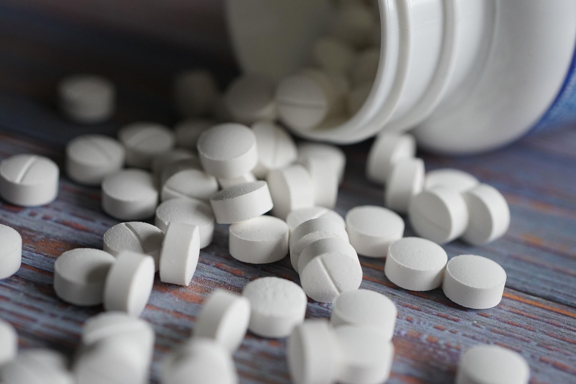 White pills spilled from a prescription bottle onto a surface with a striped cloth underneath