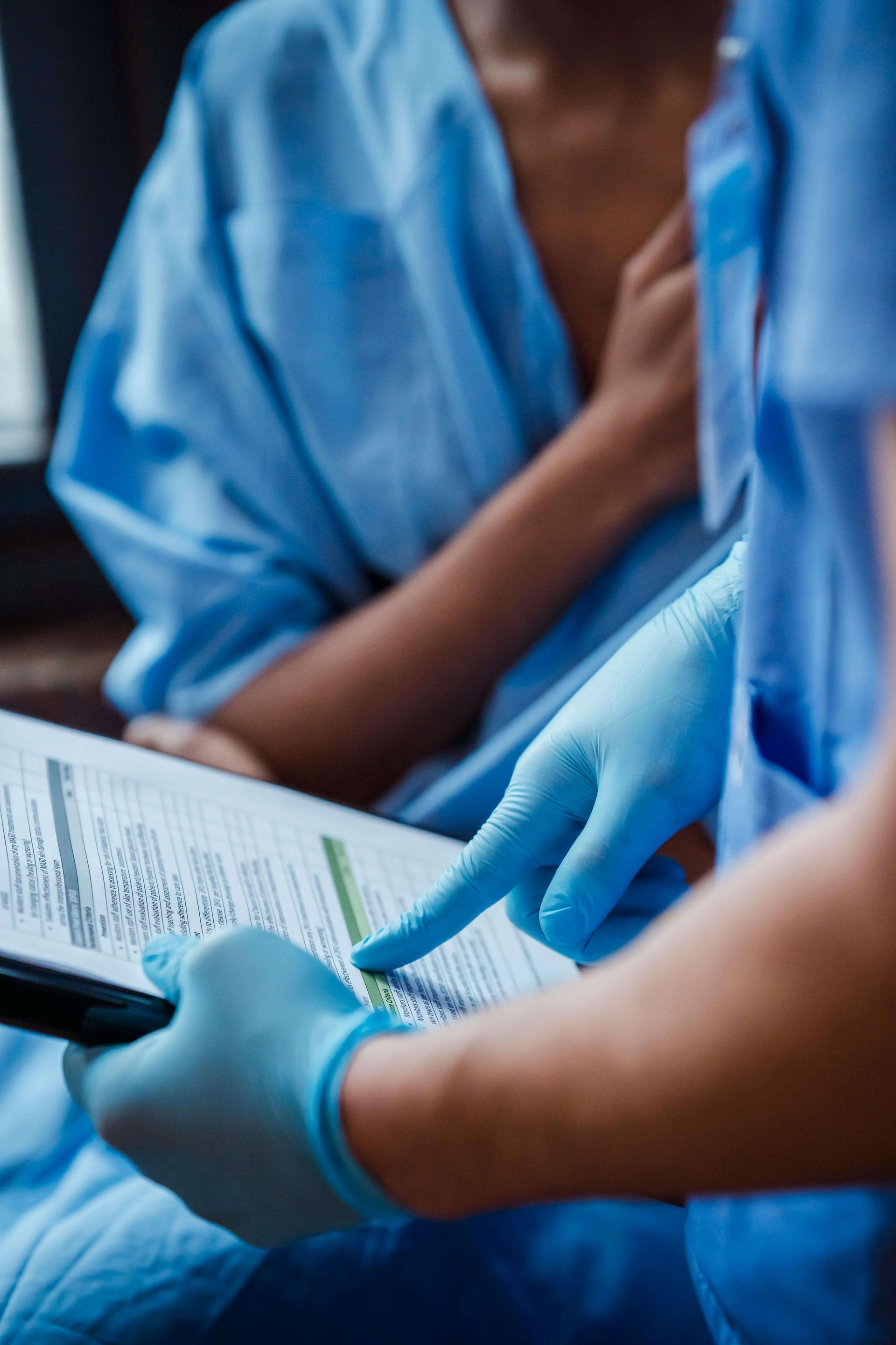 Gloved hands reviewing a form on a clipboard in a clinical setting