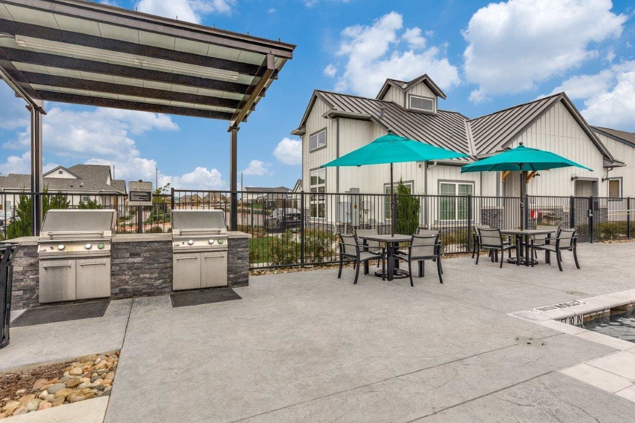 A patio with tables and chairs and umbrellas.