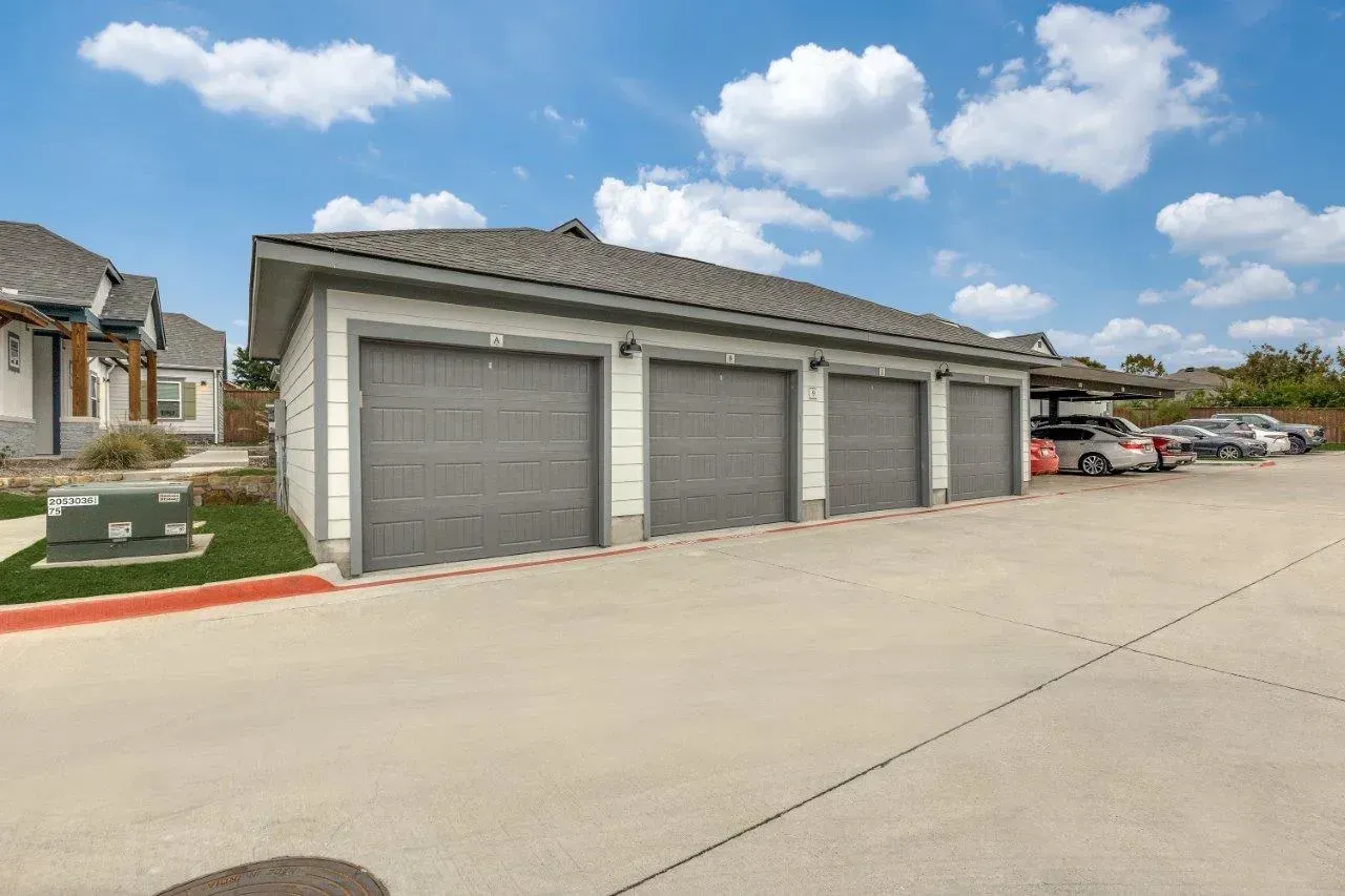 A row of garages with cars parked in front of them.