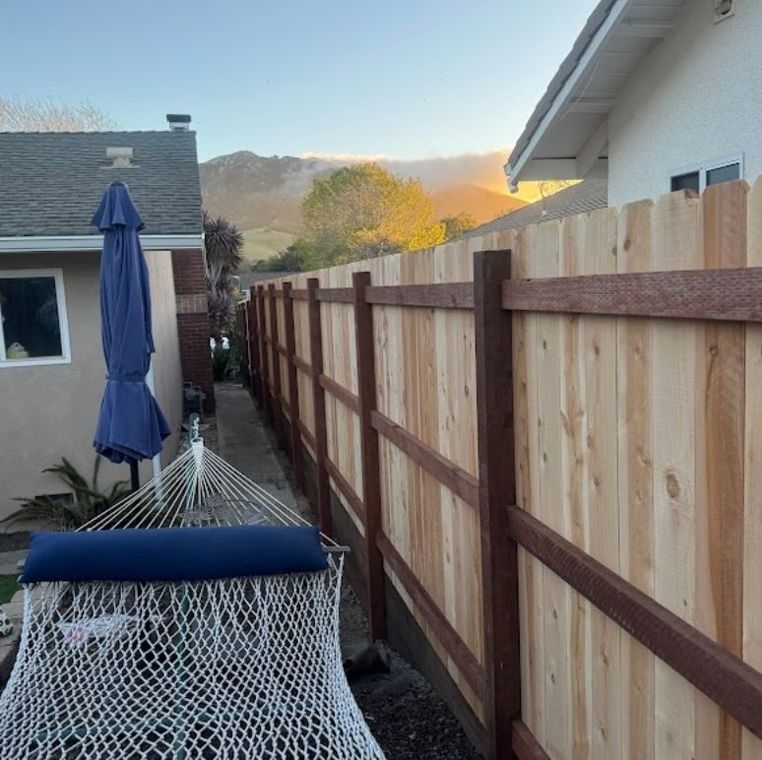 Backyard patio with a wooden fence, closed blue umbrella, hammock chair, and mountain view at sunset