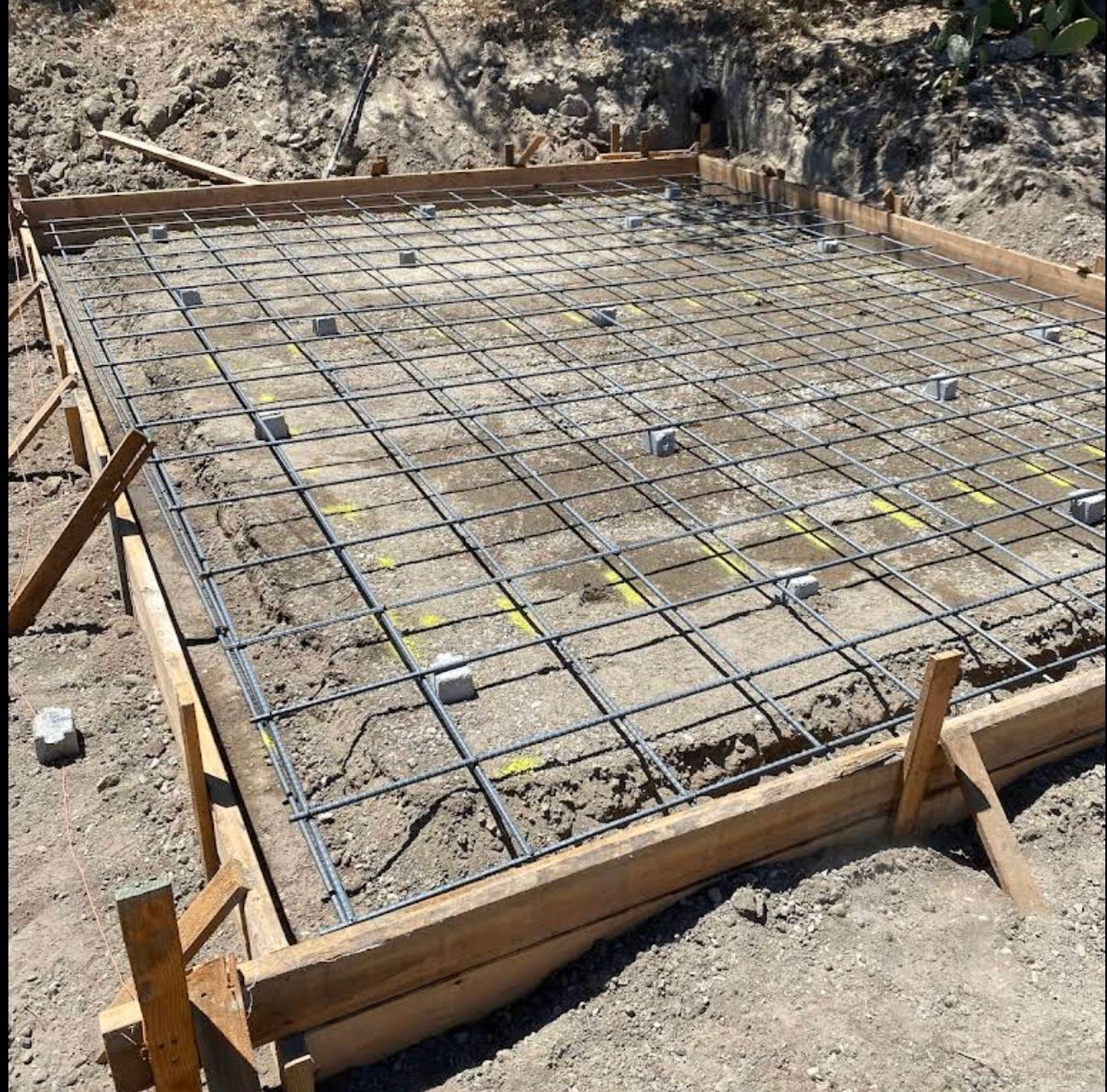 Rebar grid in wooden forms for a concrete foundation on a dirt construction site