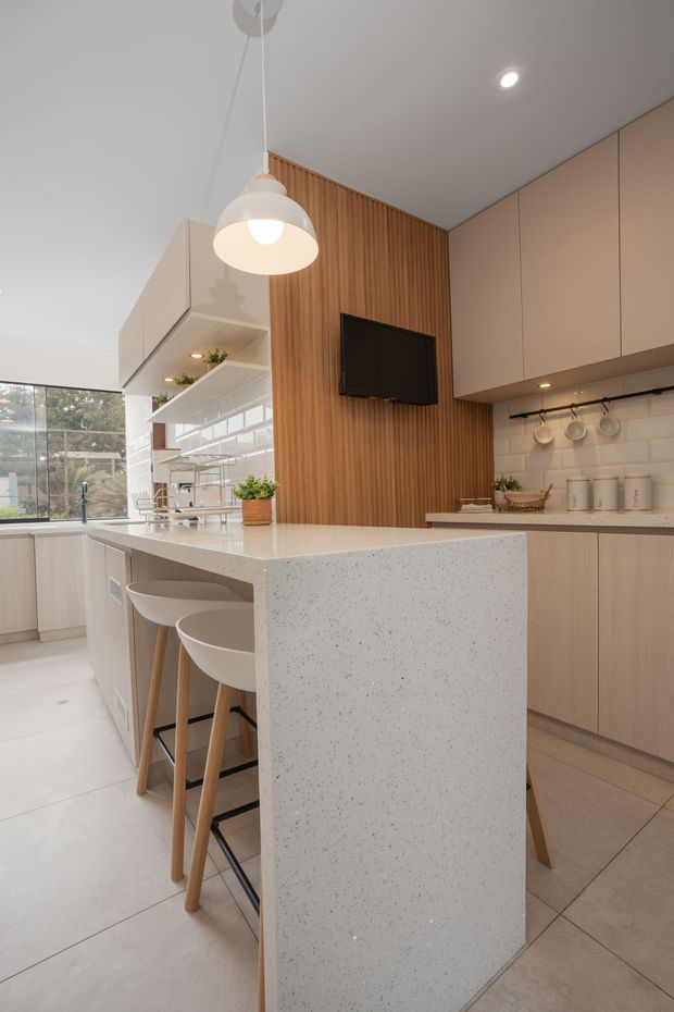 Modern kitchen island with speckled white countertop, wood slat wall, and beige cabinets