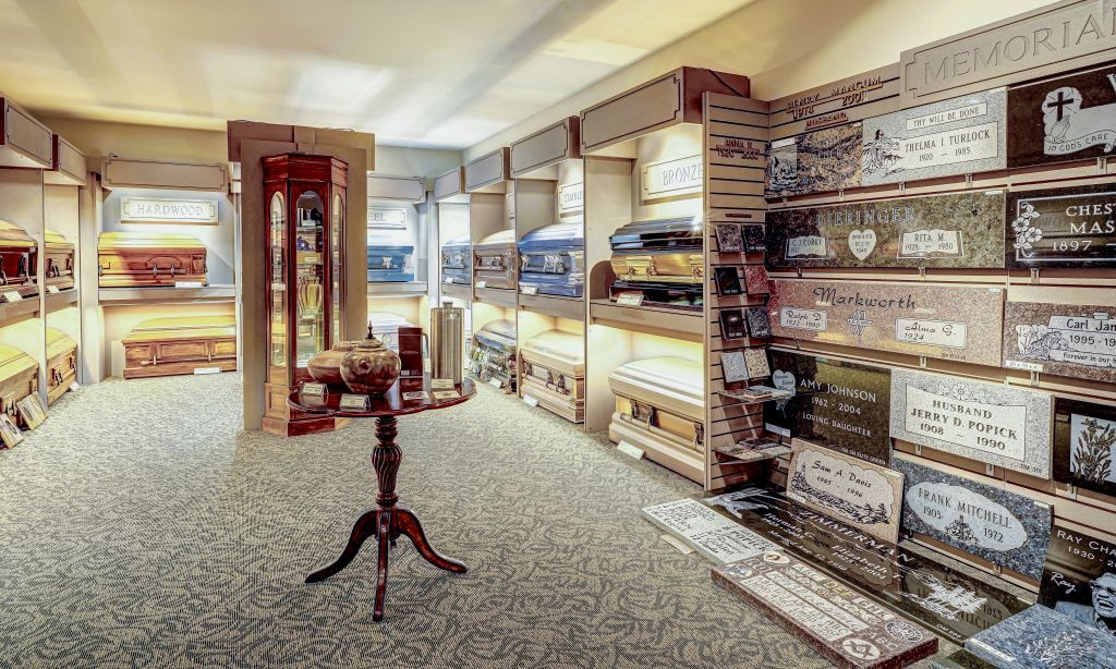 A merchandise  room filled with lots of coffins and a table.