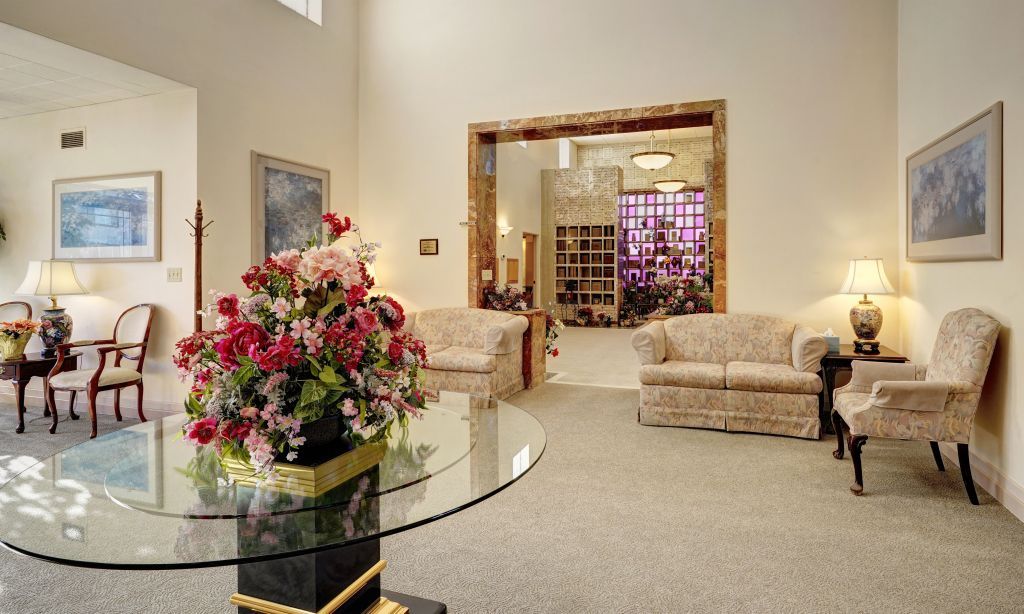 A living room with a glass table and a vase of flowers