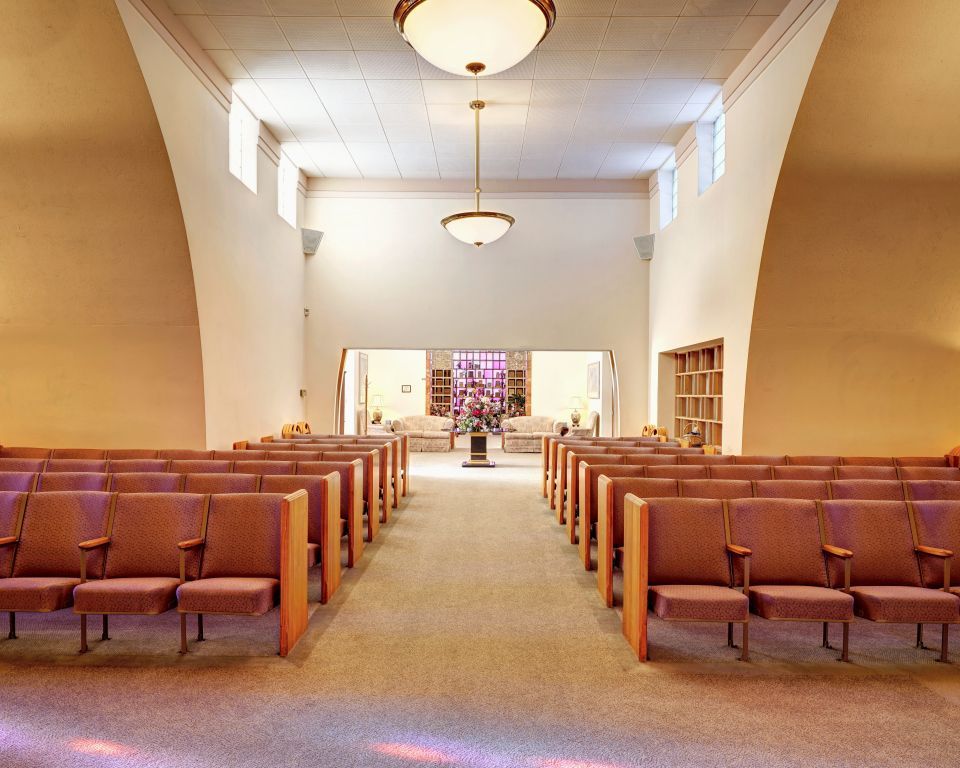 An empty church with rows of chairs and a stained glass window
