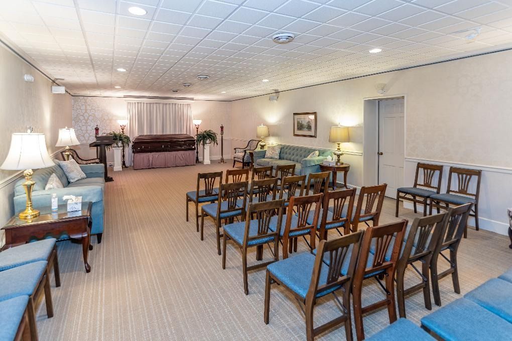 Bright lounge with blue chairs, wooden tables, lamps, and sofas under recessed ceiling lights.