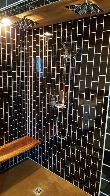 A bathroom with black tiles and a wooden bench.