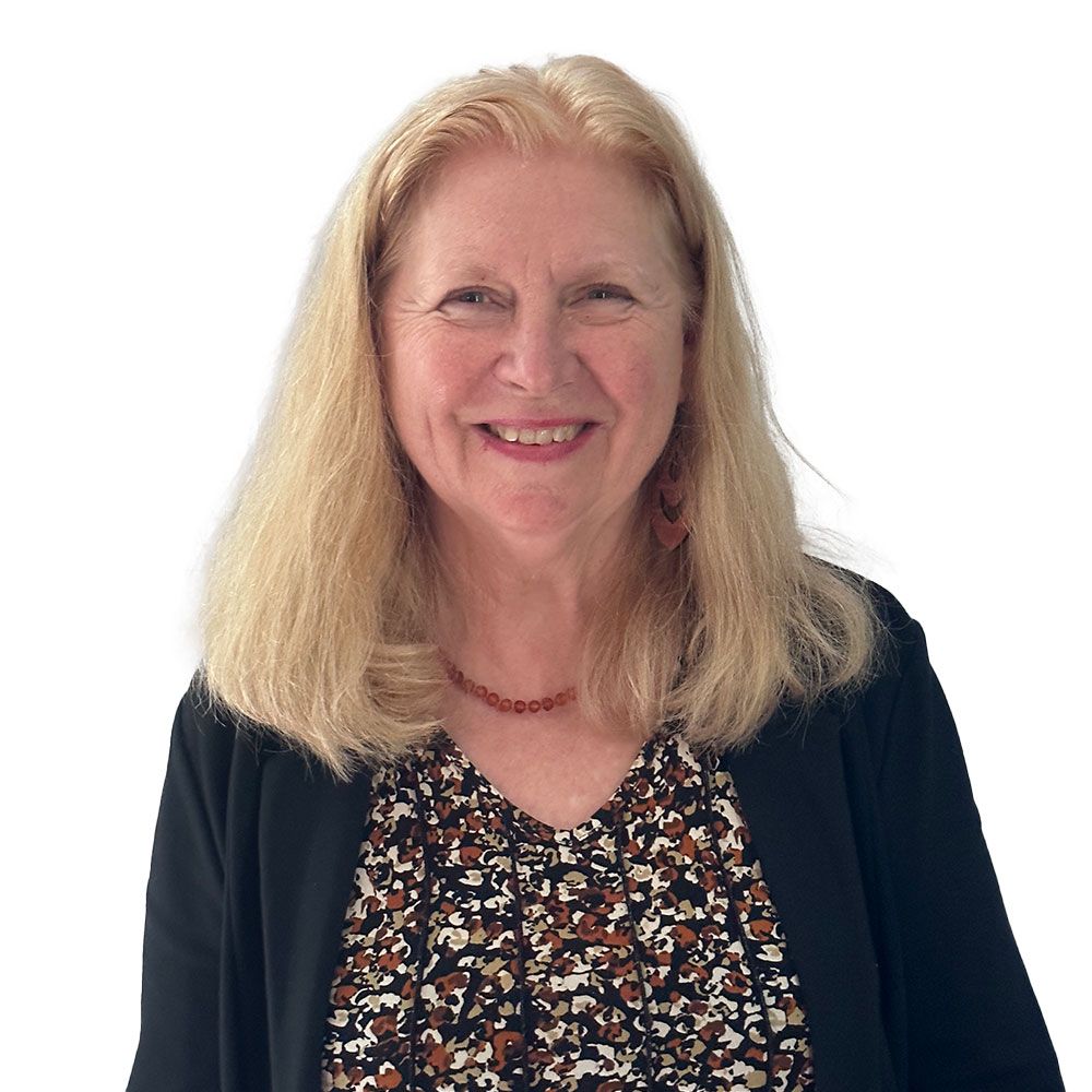 A woman wearing a black cardigan and a necklace is smiling for the camera.
