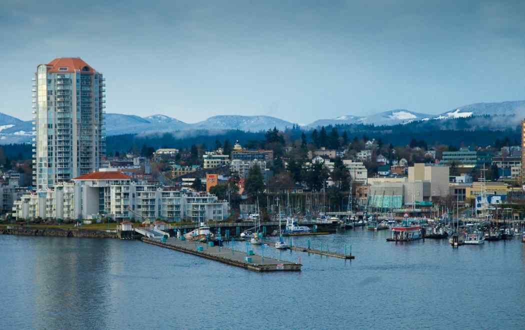 Harbor waterfront skyline with high-rise apartments, boats, and mountains in the background