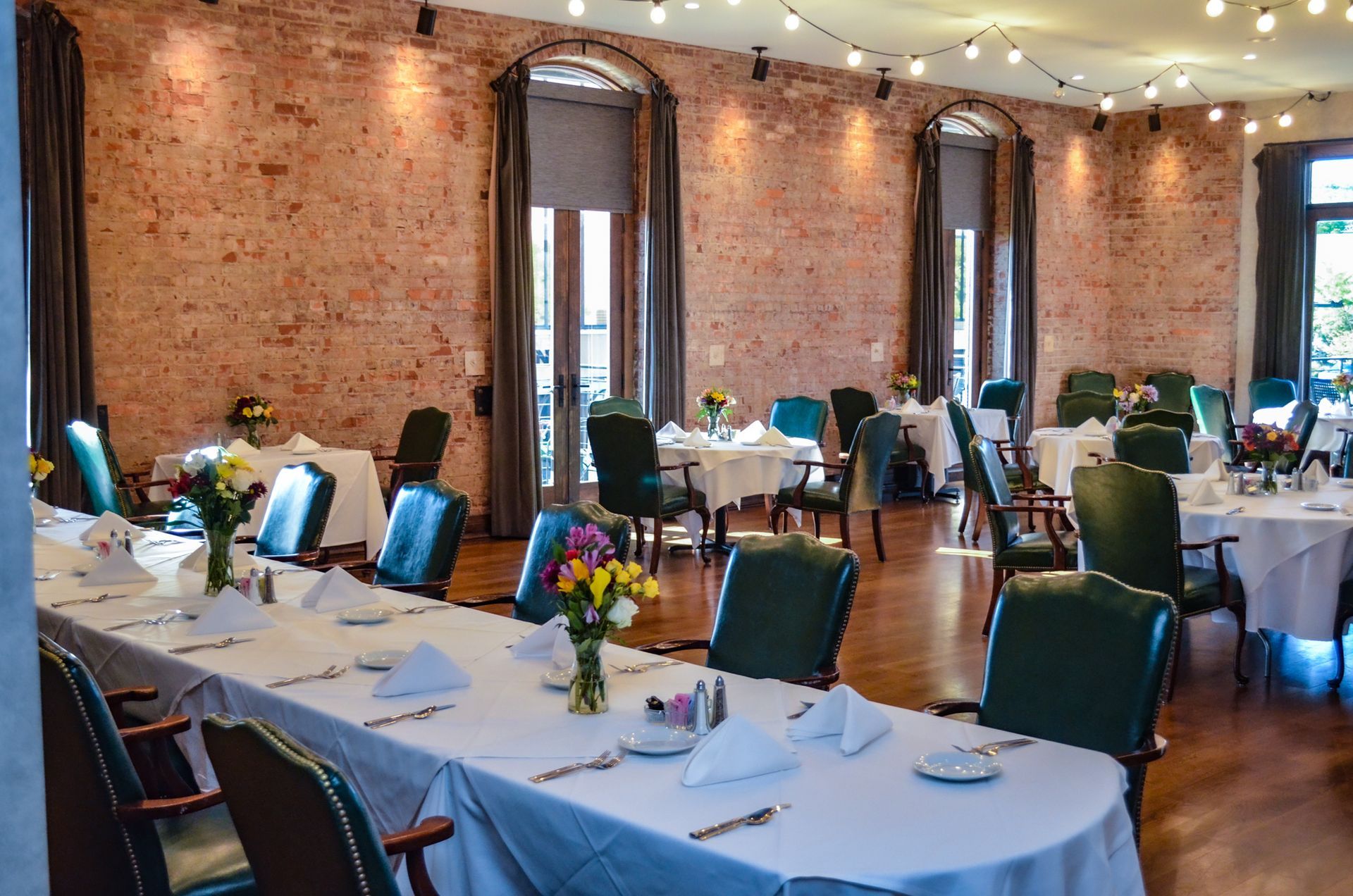 A large dining room with tables and chairs and a brick wall.