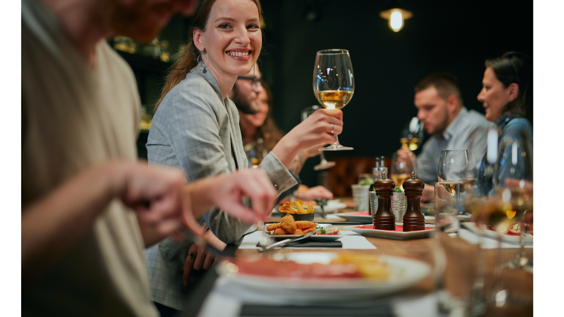A group of people are sitting at a table eating food and drinking wine.