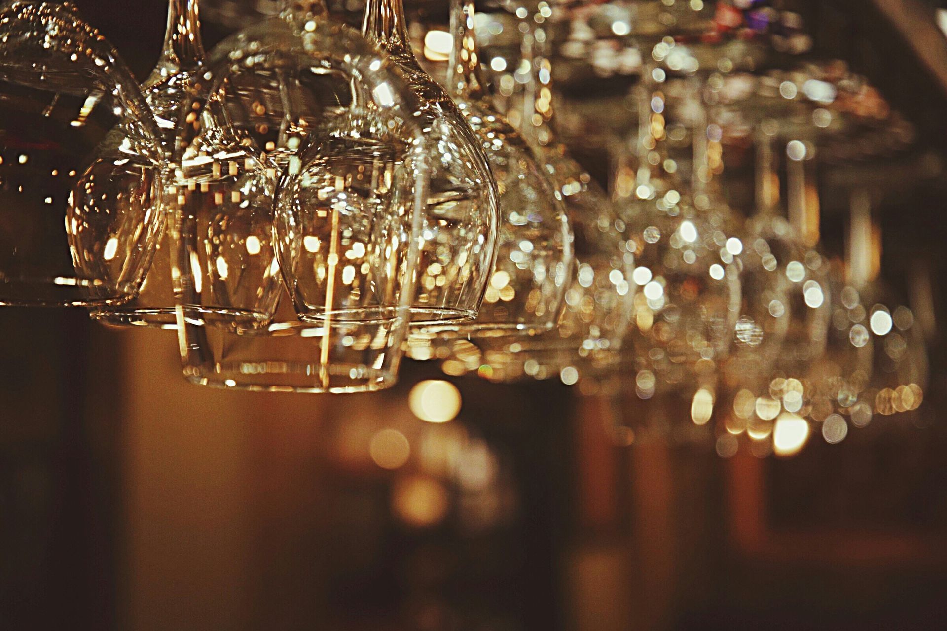 A bunch of wine glasses hanging from the ceiling in a bar.