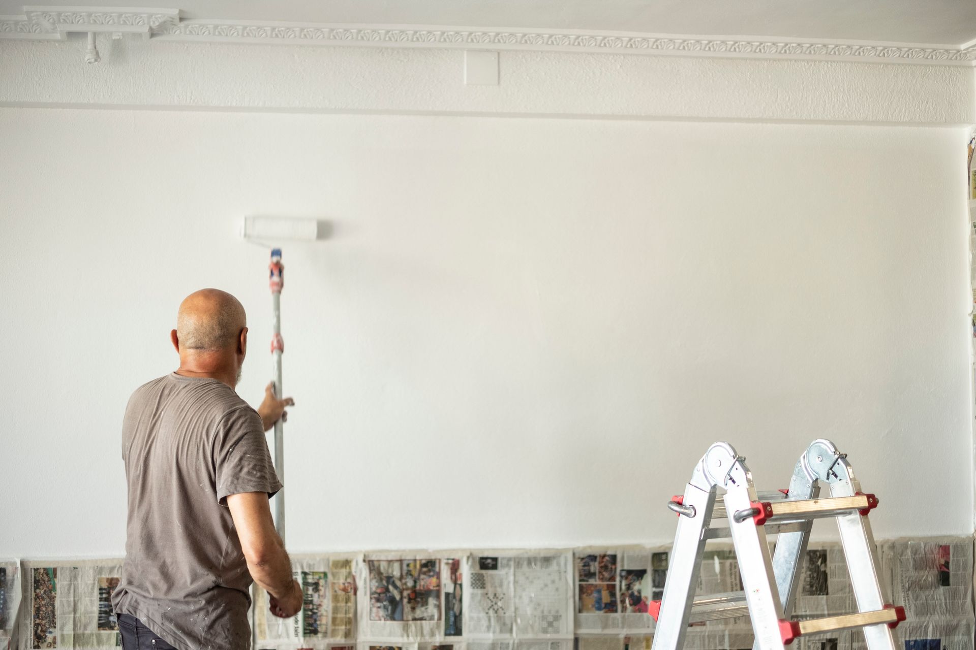 A person is painting a metal railing with green paint.