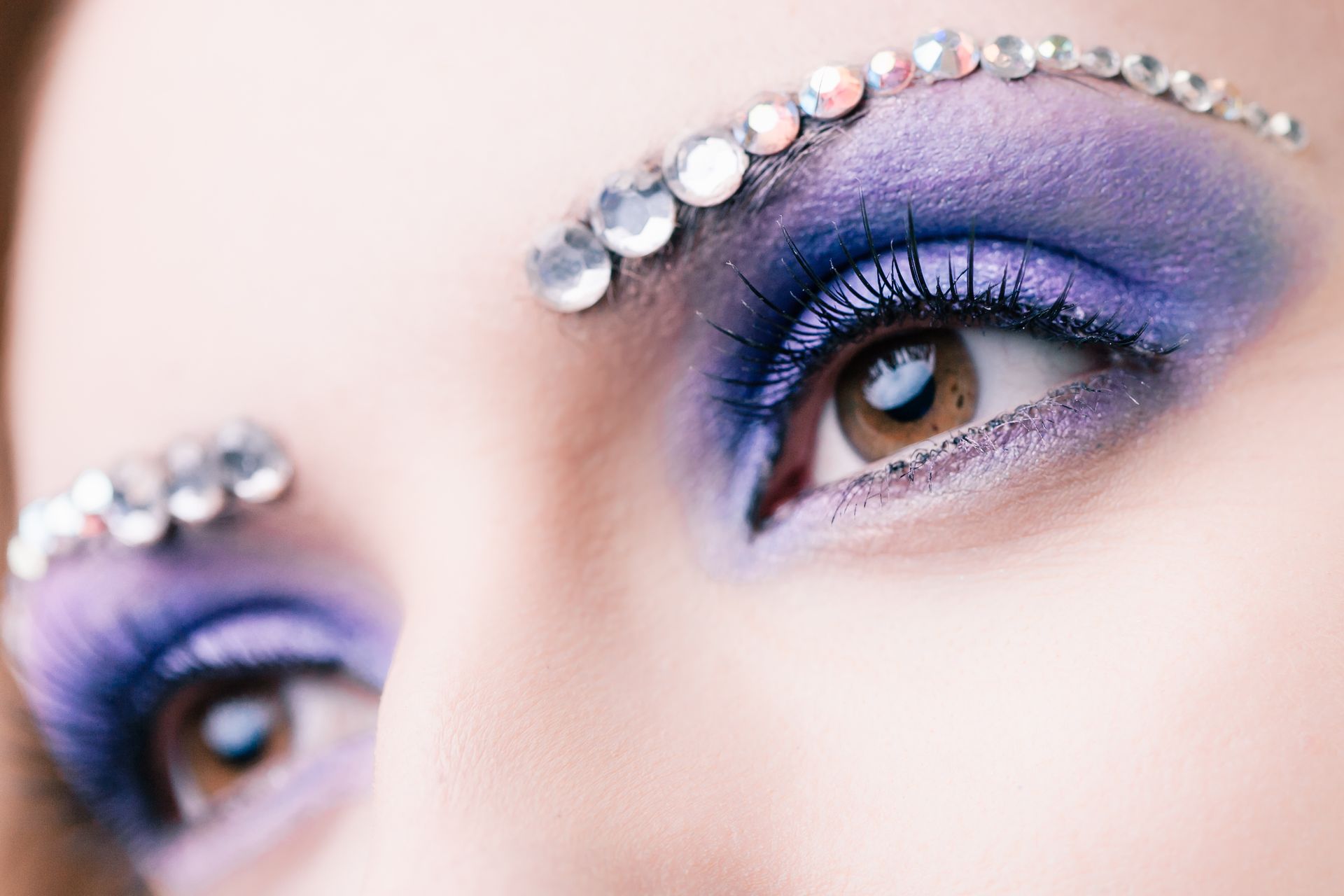 Eyes with purple eyeshadow and crystal accents on brows.