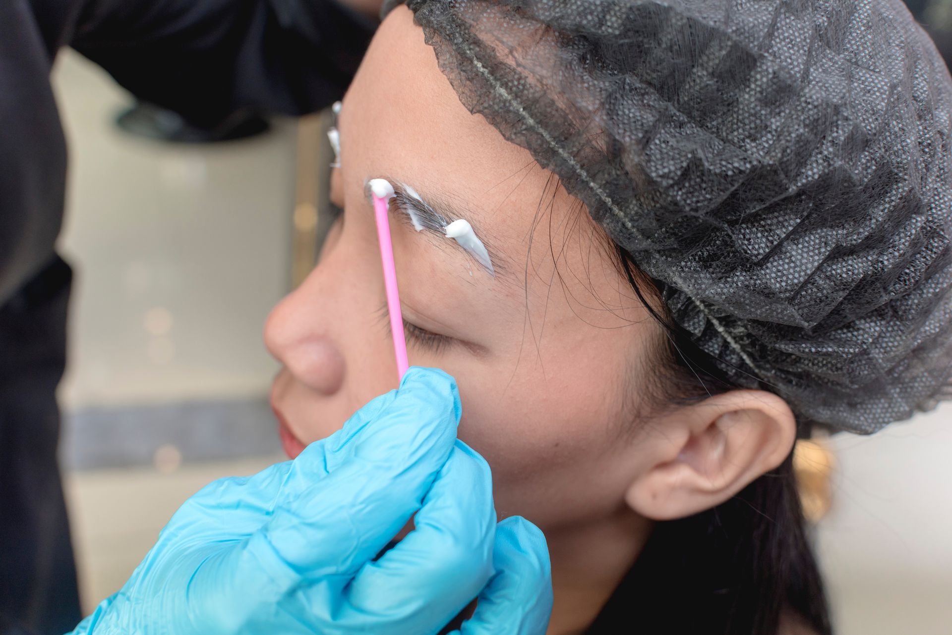 Nano Brow Artist Applying Numbing Cream to Eyebrows Before Microblading Procedure