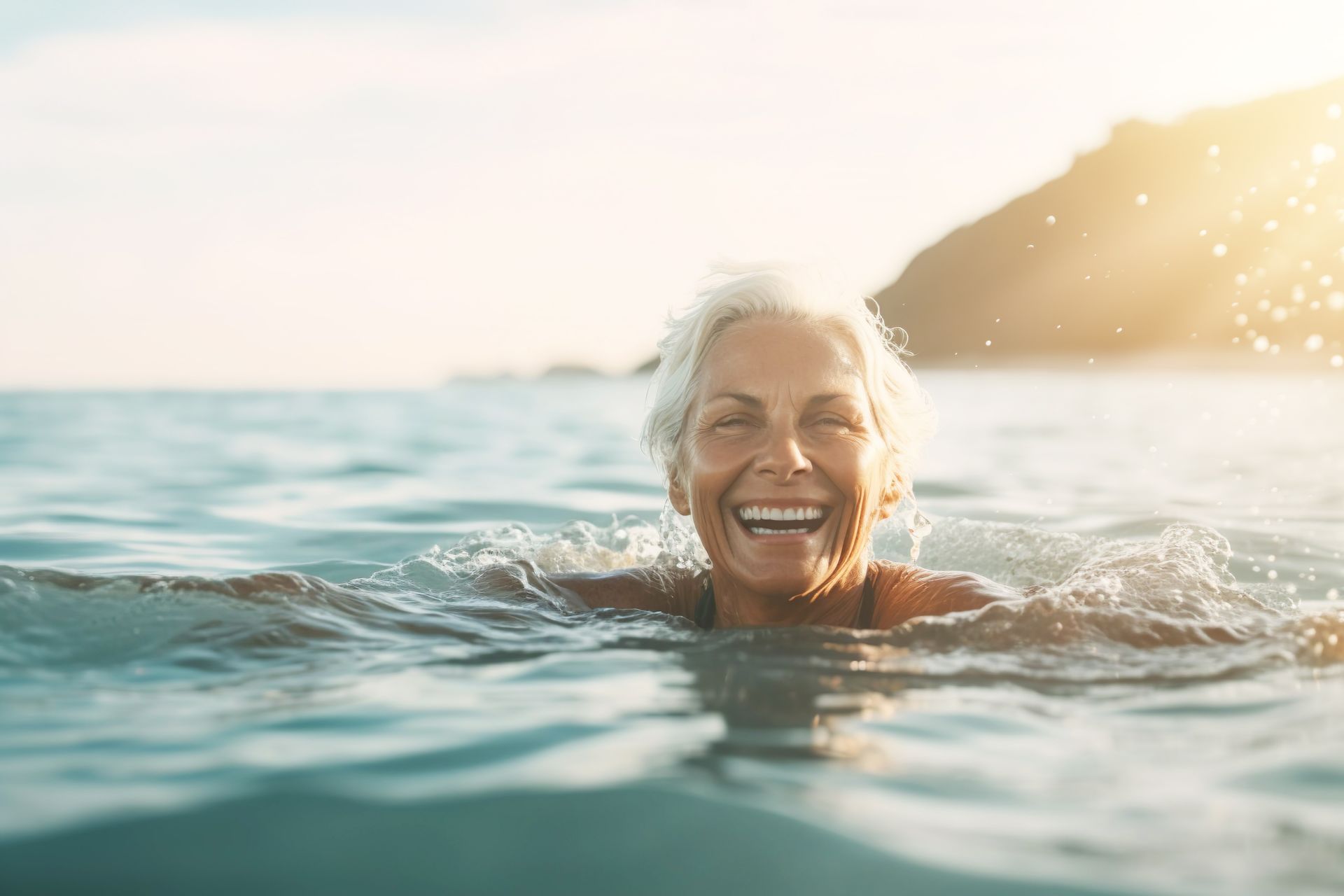 A woman is swimming in the ocean and smiling.