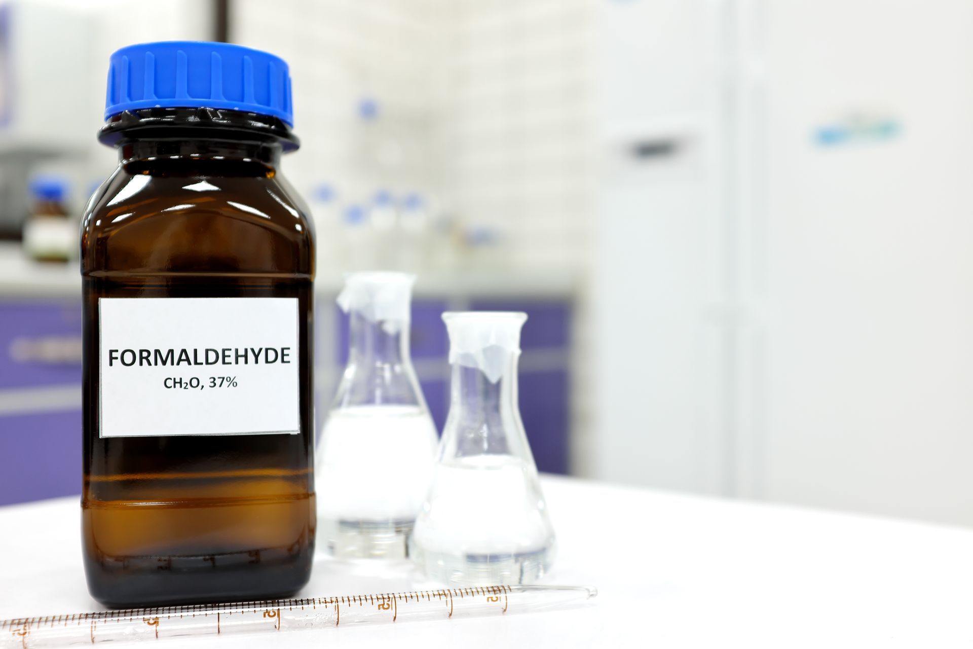 A bottle of formaldehyde is sitting on a table next to beakers.