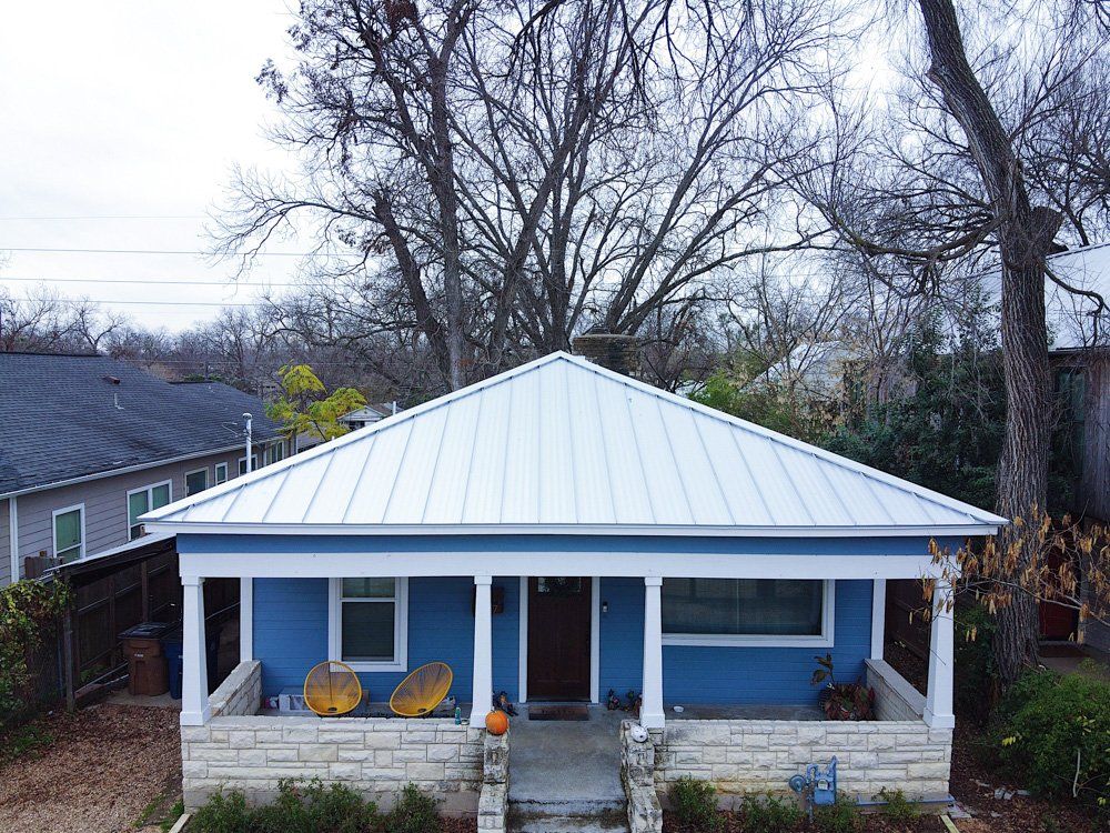 an aerial view of a blue house with a white roof and a porch .