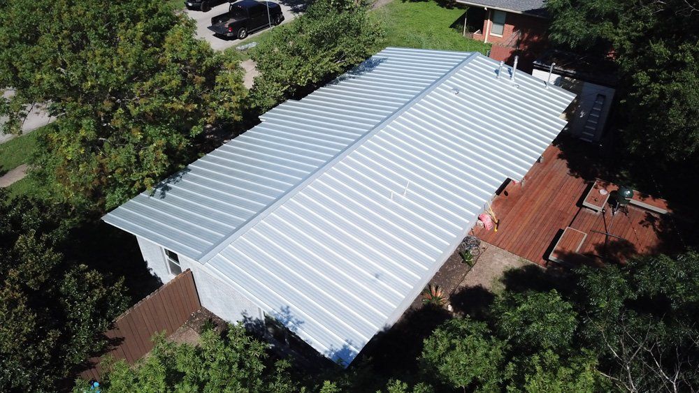 an aerial view of a house with a metal roof surrounded by trees .