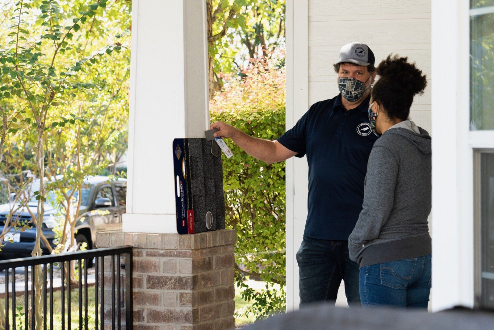 Birdcreek Roofing consultant working with homeowner on front porch