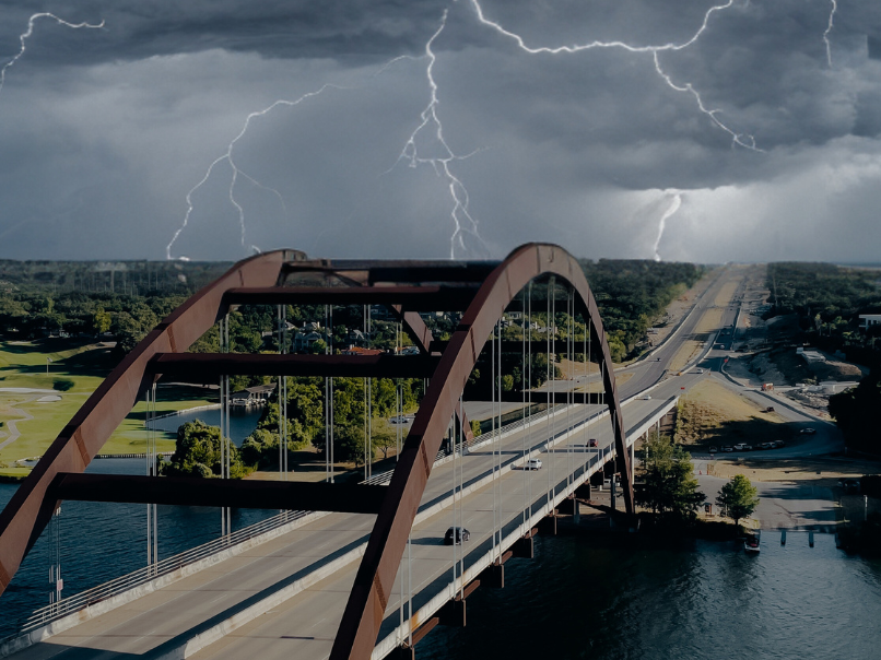 Twin-arch bridge over water under a dramatic sky with lightning in the distance