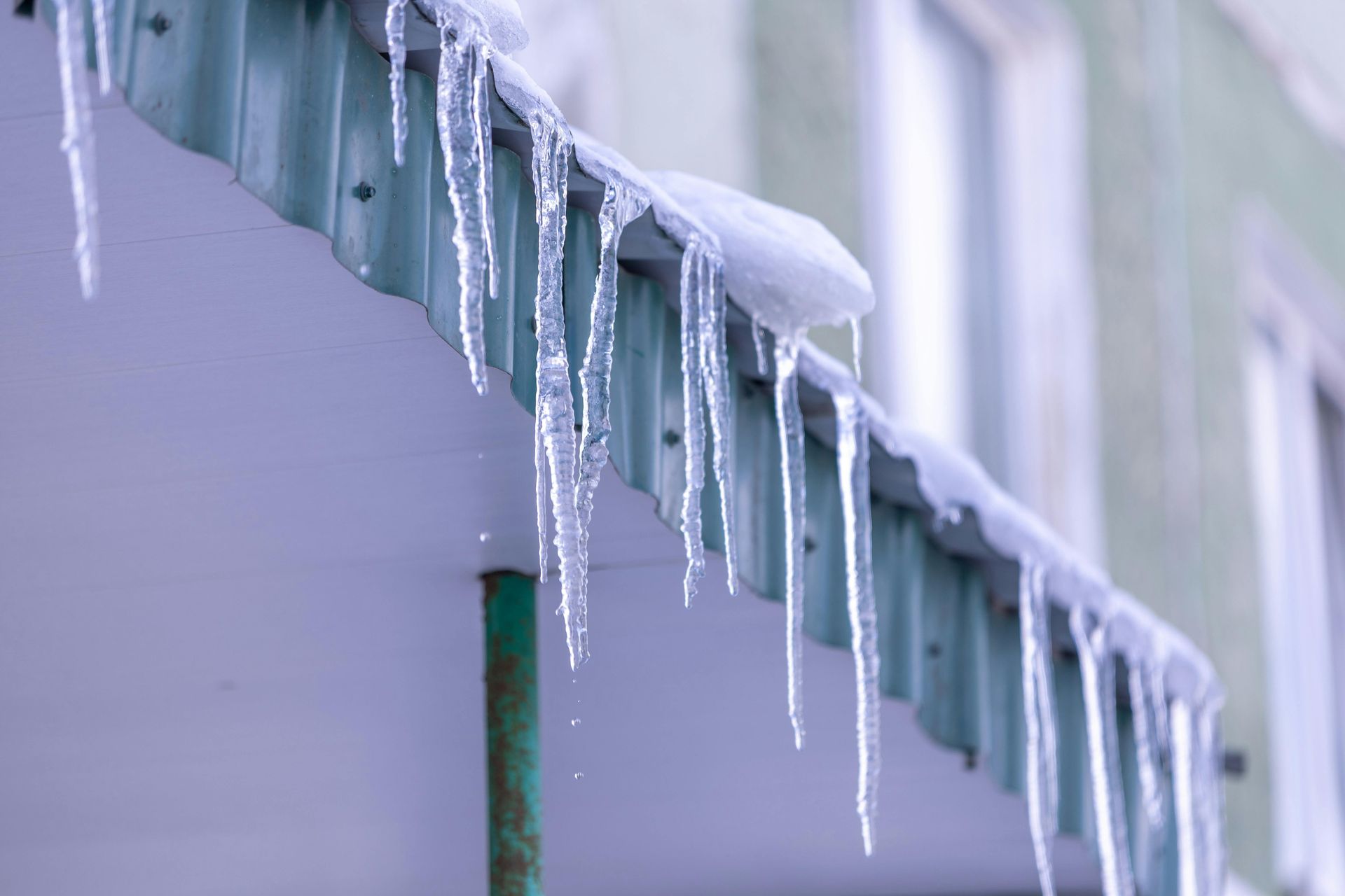Icicles hanging from a green-roofed building in winter.