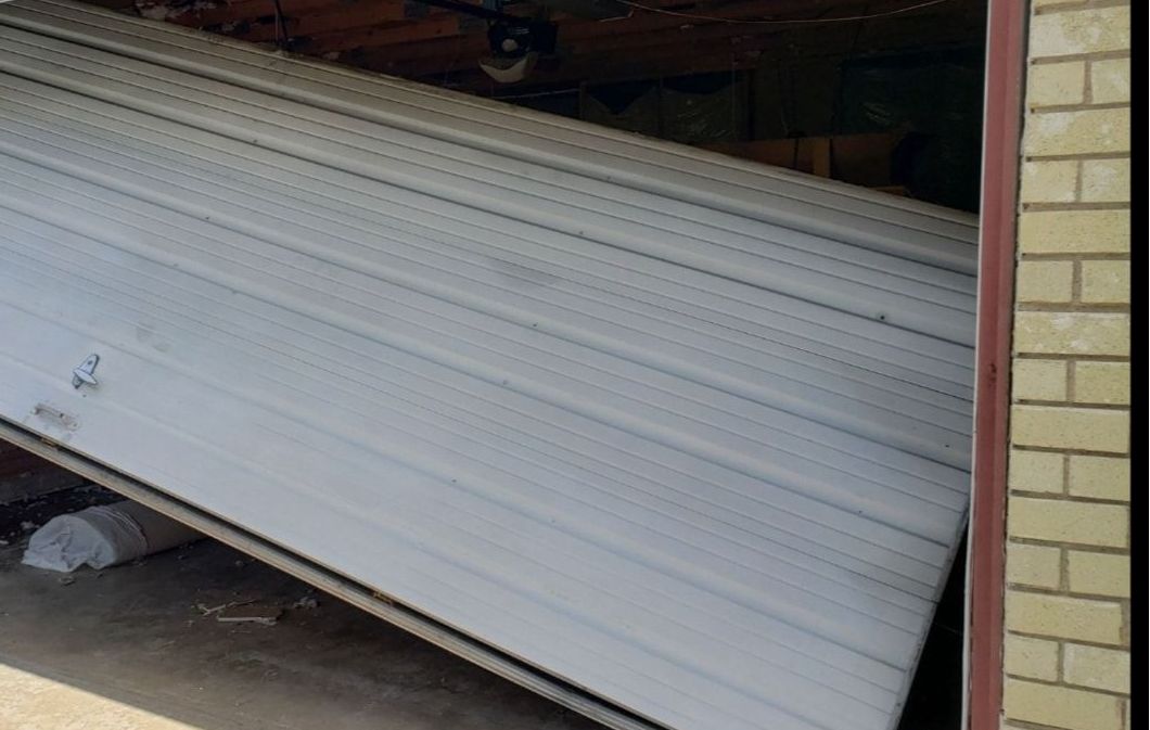 Garage door, partially open and tilted, showing the inside of the garage.